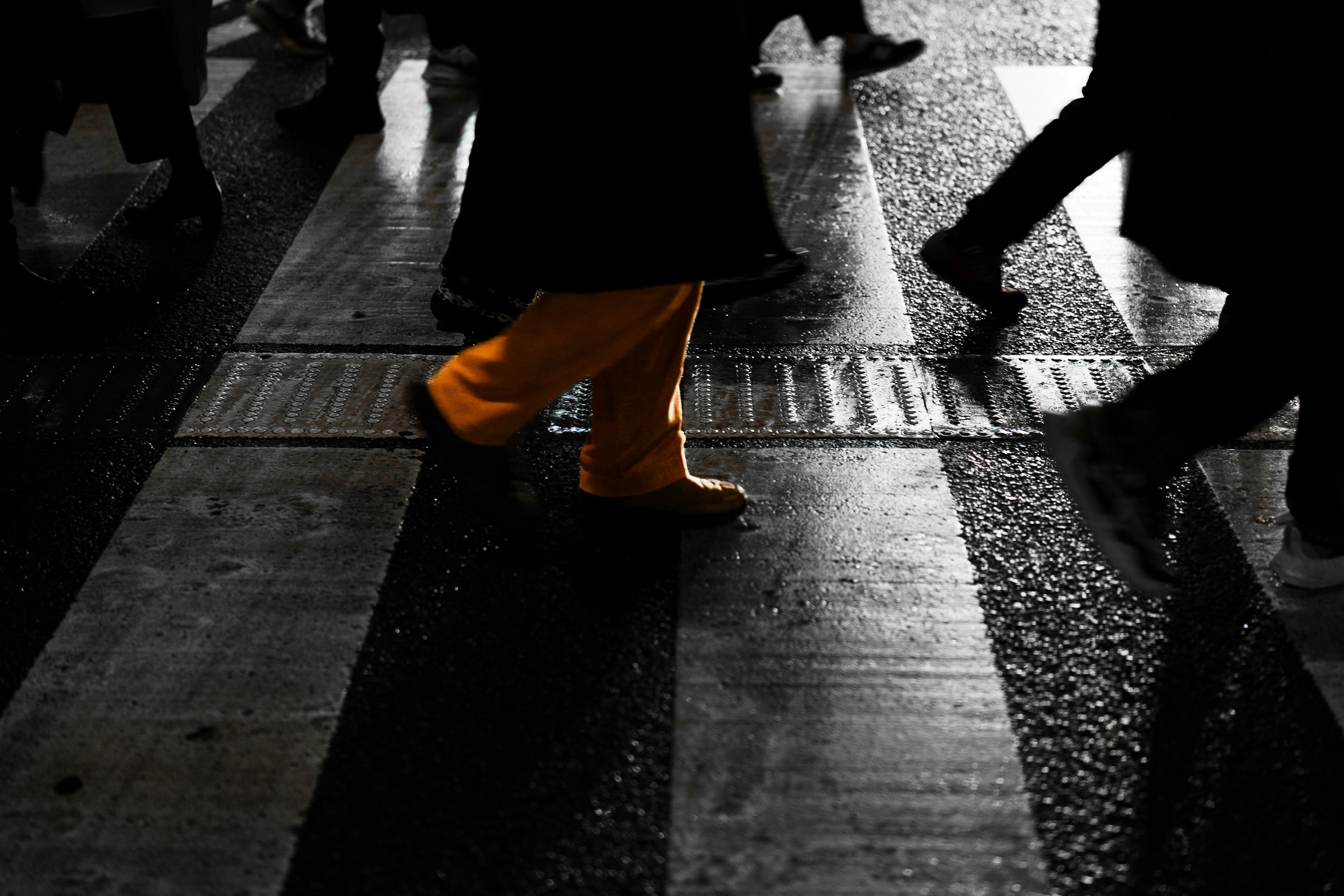 Silhouettes of people crossing a street with a focus on a leg in yellow pants