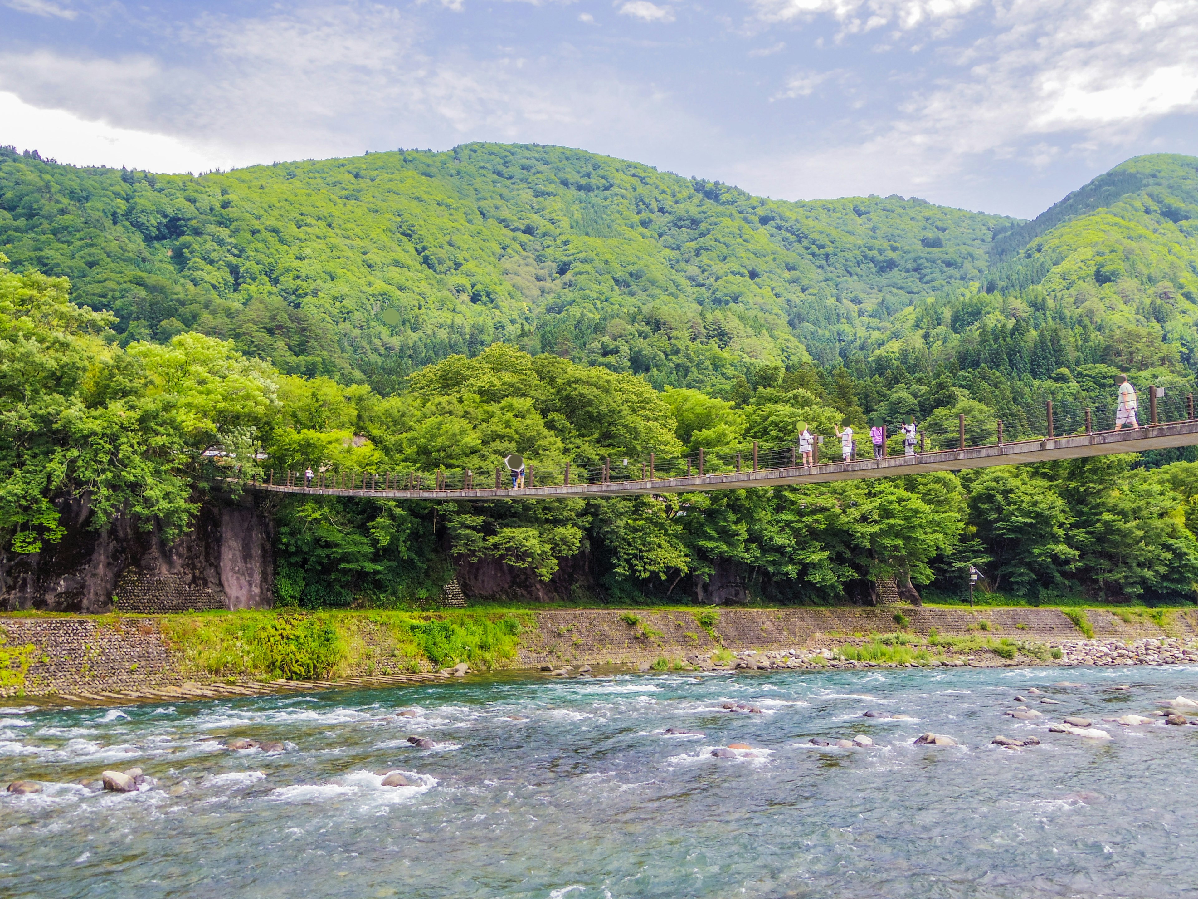 Vista escénica de un puente colgante sobre un río rodeado de montañas verdes