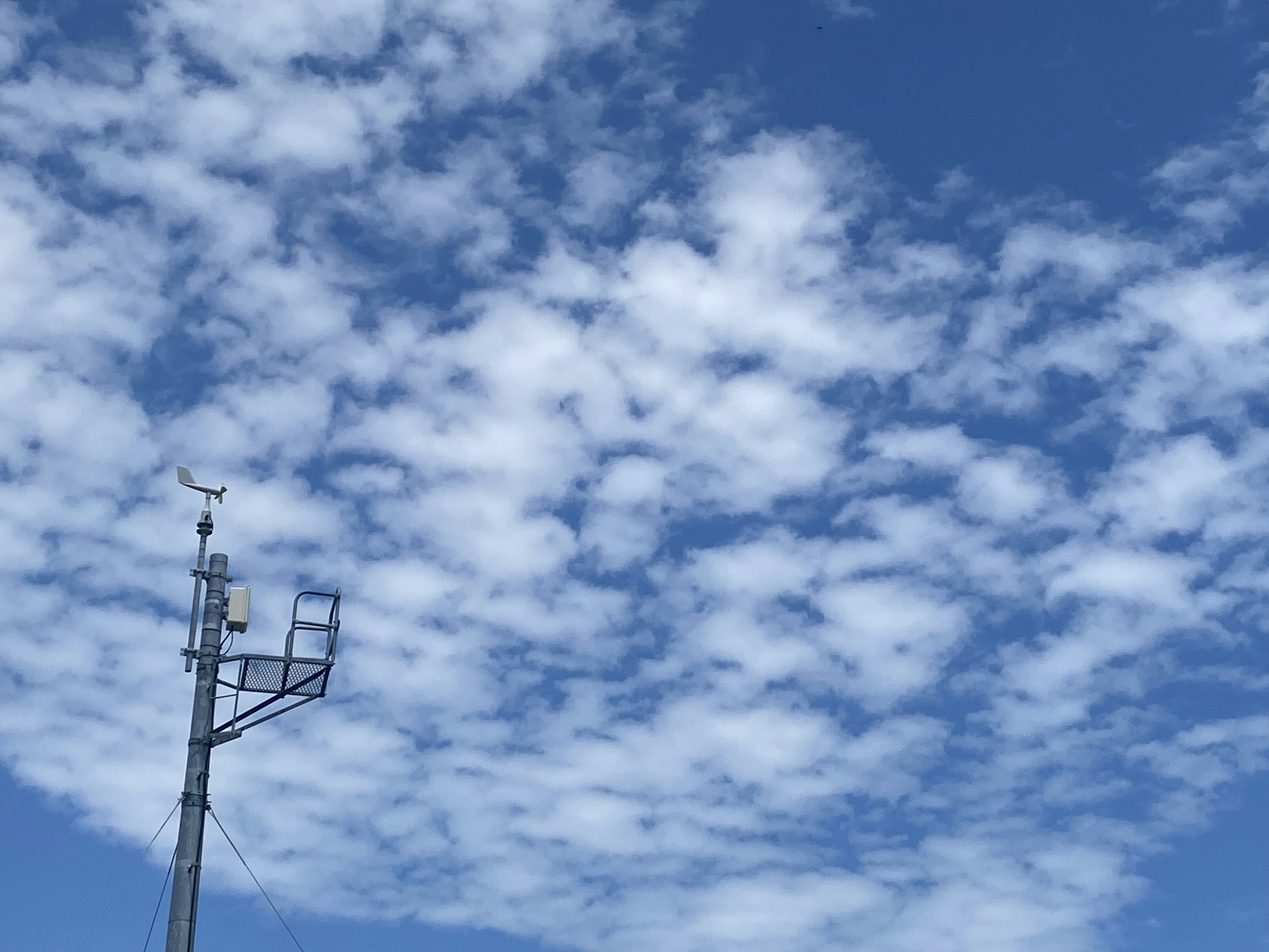 青空に浮かぶ白い雲と通信塔の風景