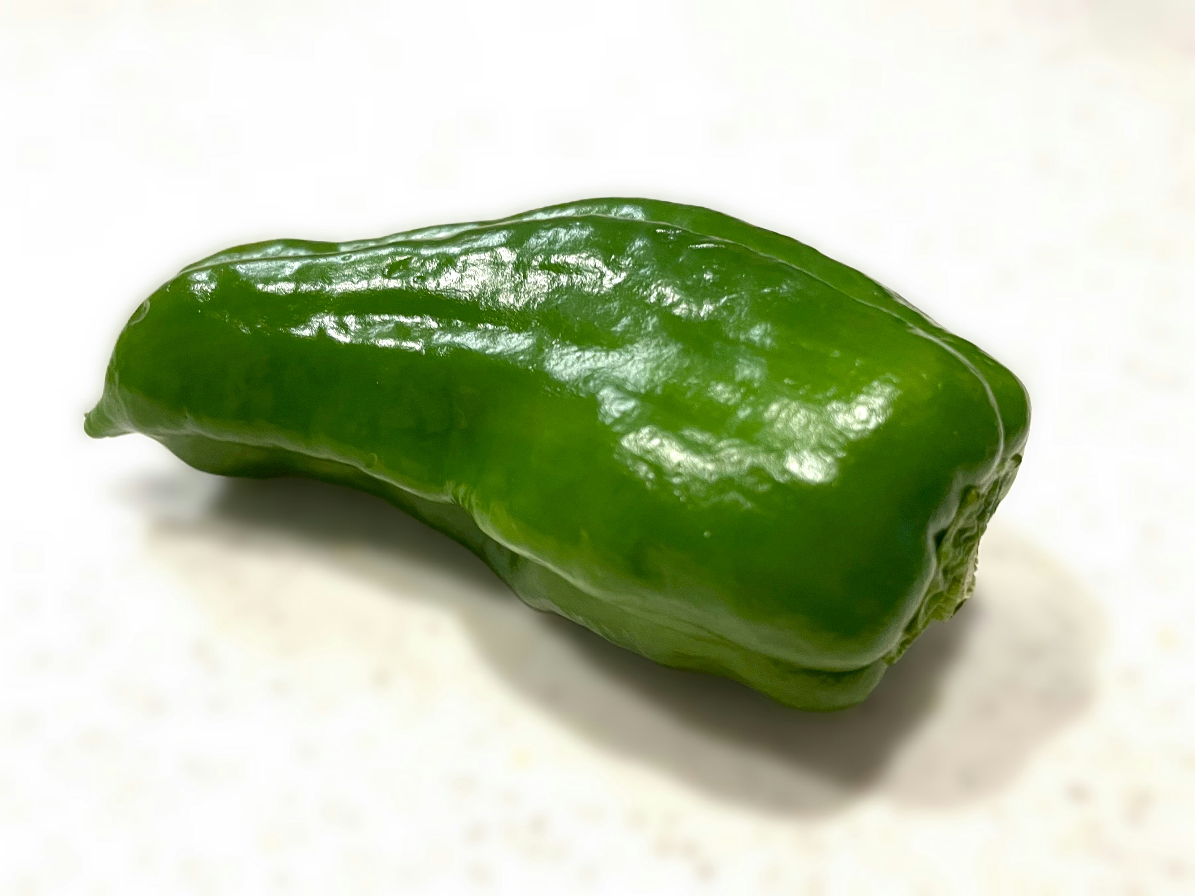 A green pepper-like vegetable placed on a white background