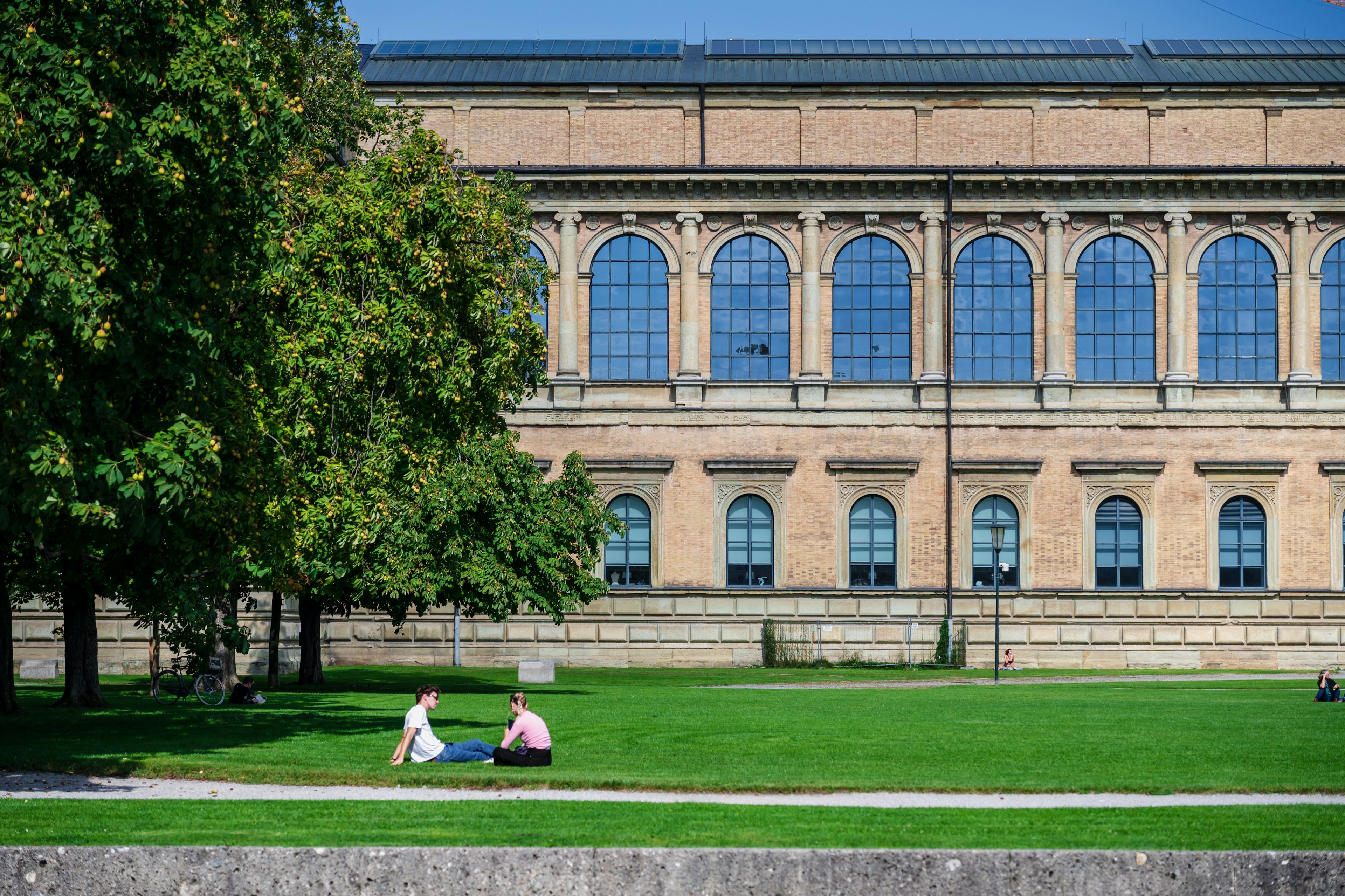 Menschen entspannen auf dem grünen Gras vor einem Museum