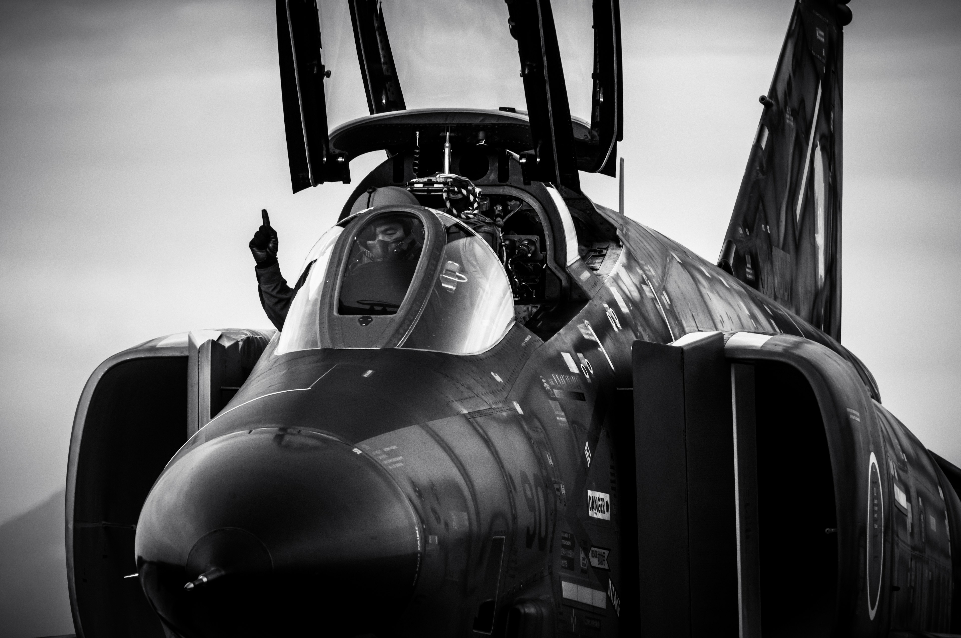 Schwarzweißbild eines Kampfjet-Cockpits mit sichtbarer Hand des Piloten