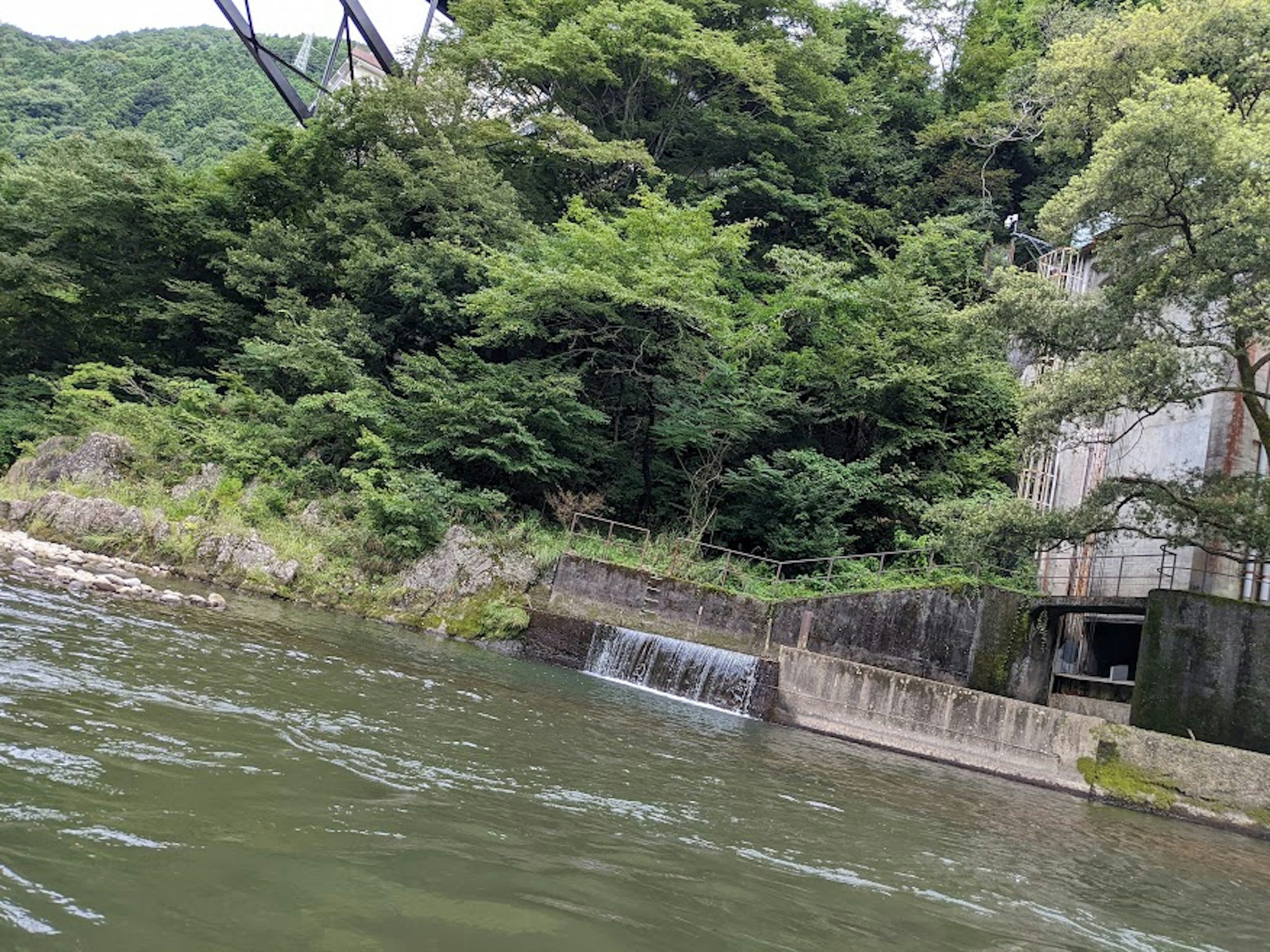 푸르른 산과 물가에 있는 콘크리트 구조물의 경치