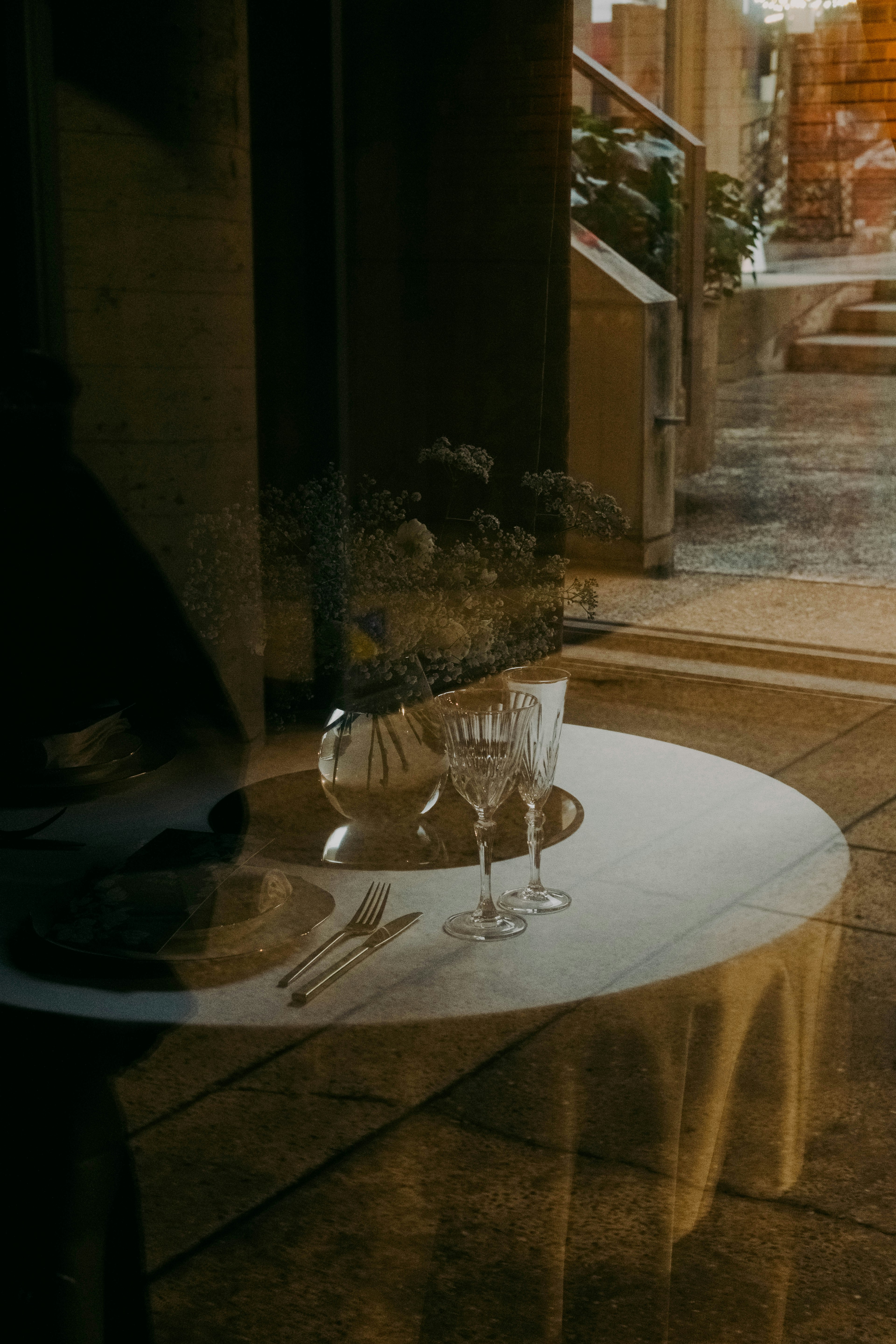 Une vue à travers le verre montrant une table dressée avec des verres en cristal et des assiettes