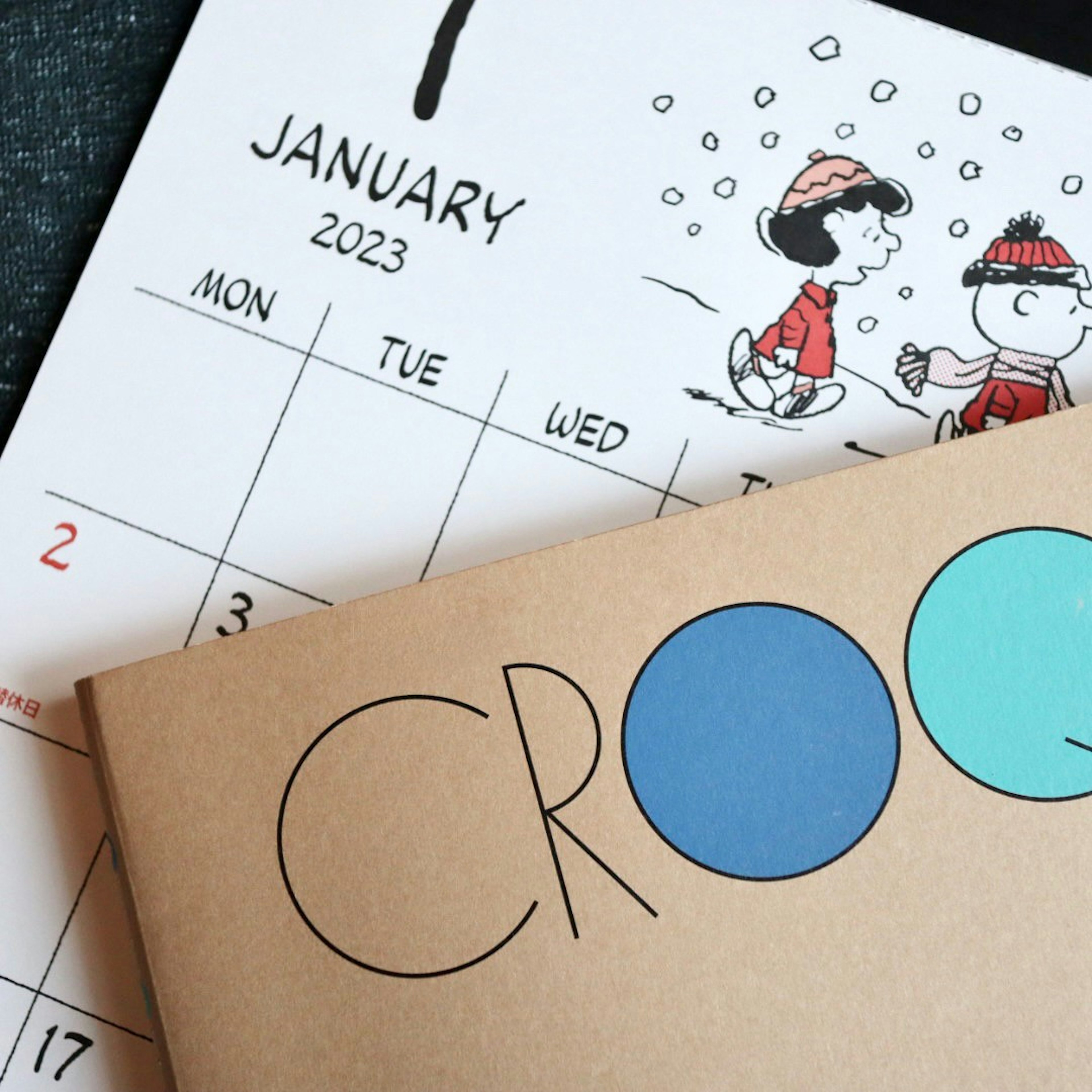 January 2023 calendar featuring cartoon characters and a brown notebook with the word 'CROO'