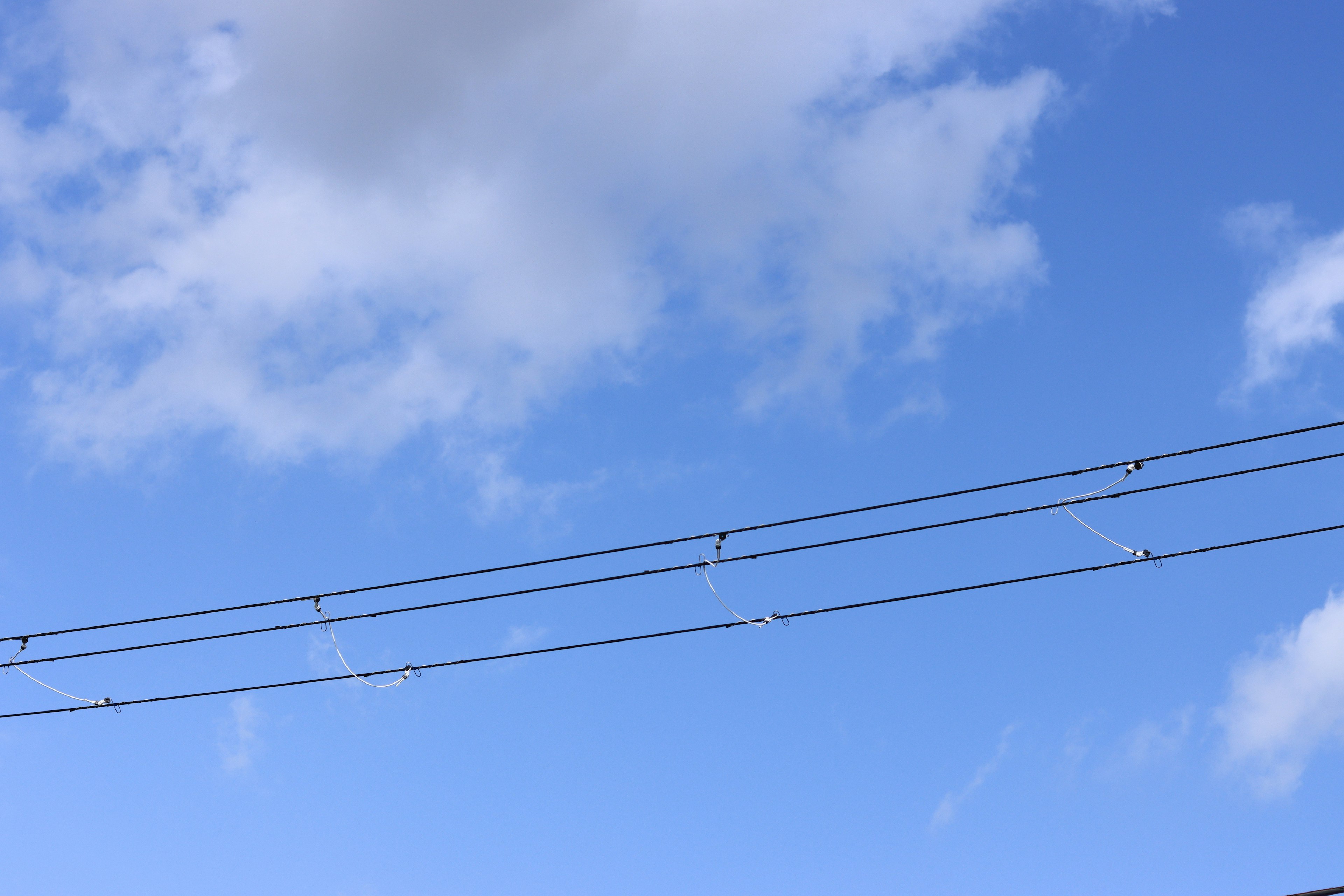 青空と白い雲の背景に架かる電線