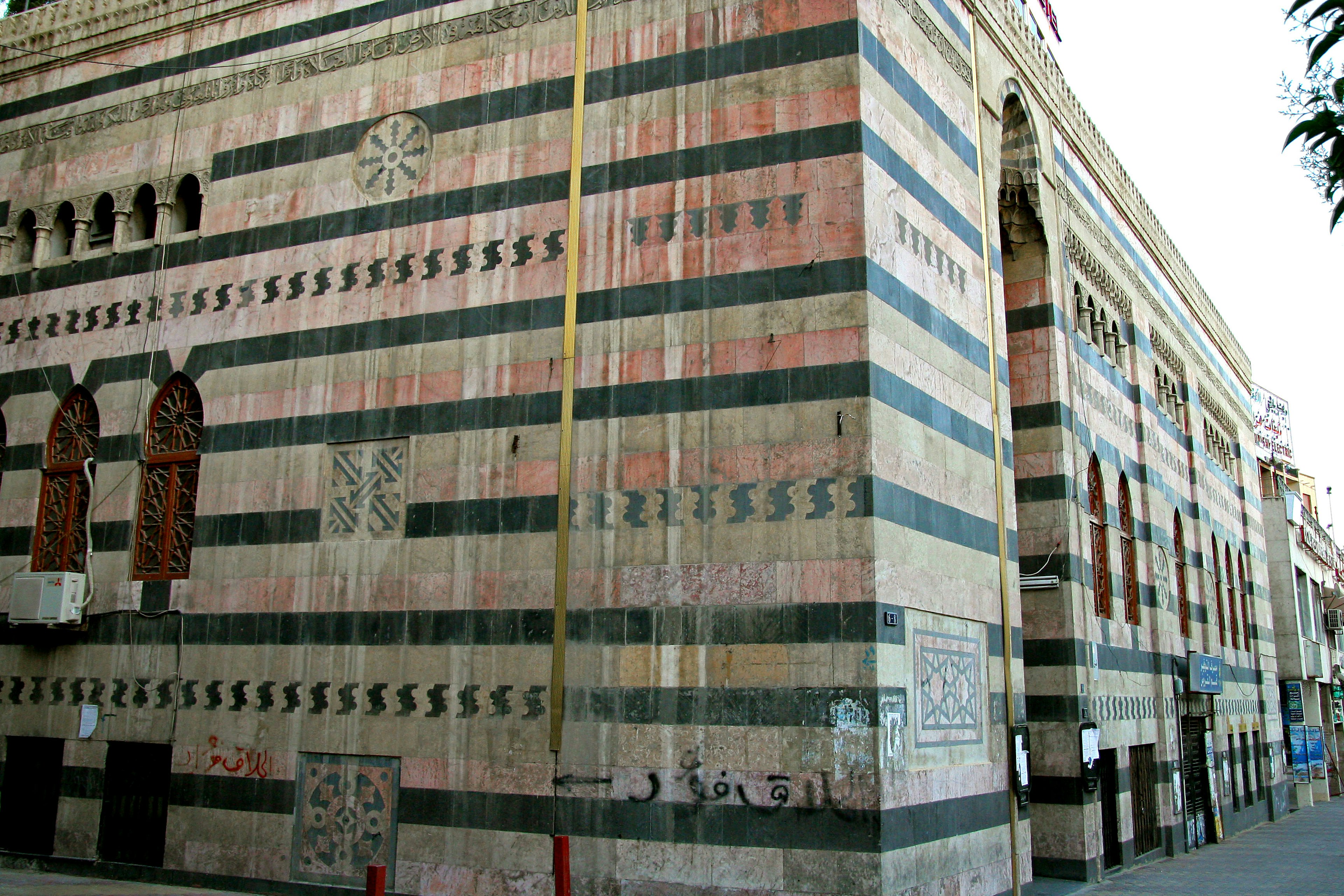 Pared exterior de un edificio con rayas coloridas y elementos decorativos