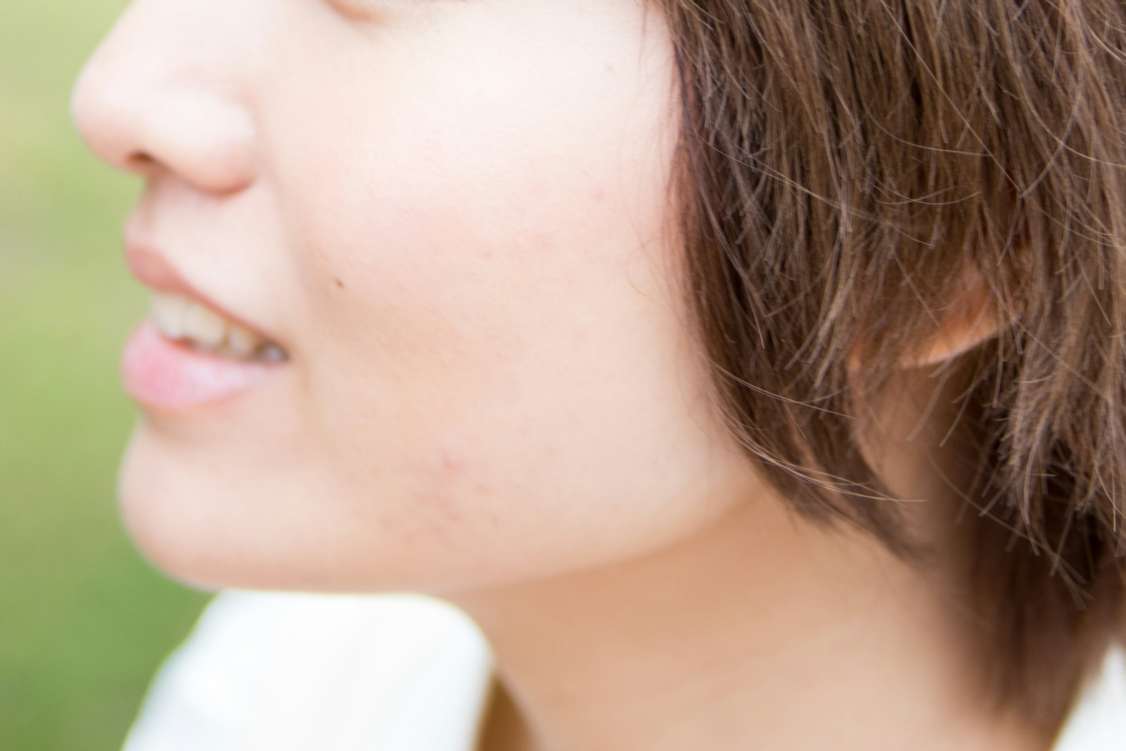 Close-up of a woman's profile smiling in natural light with short hair