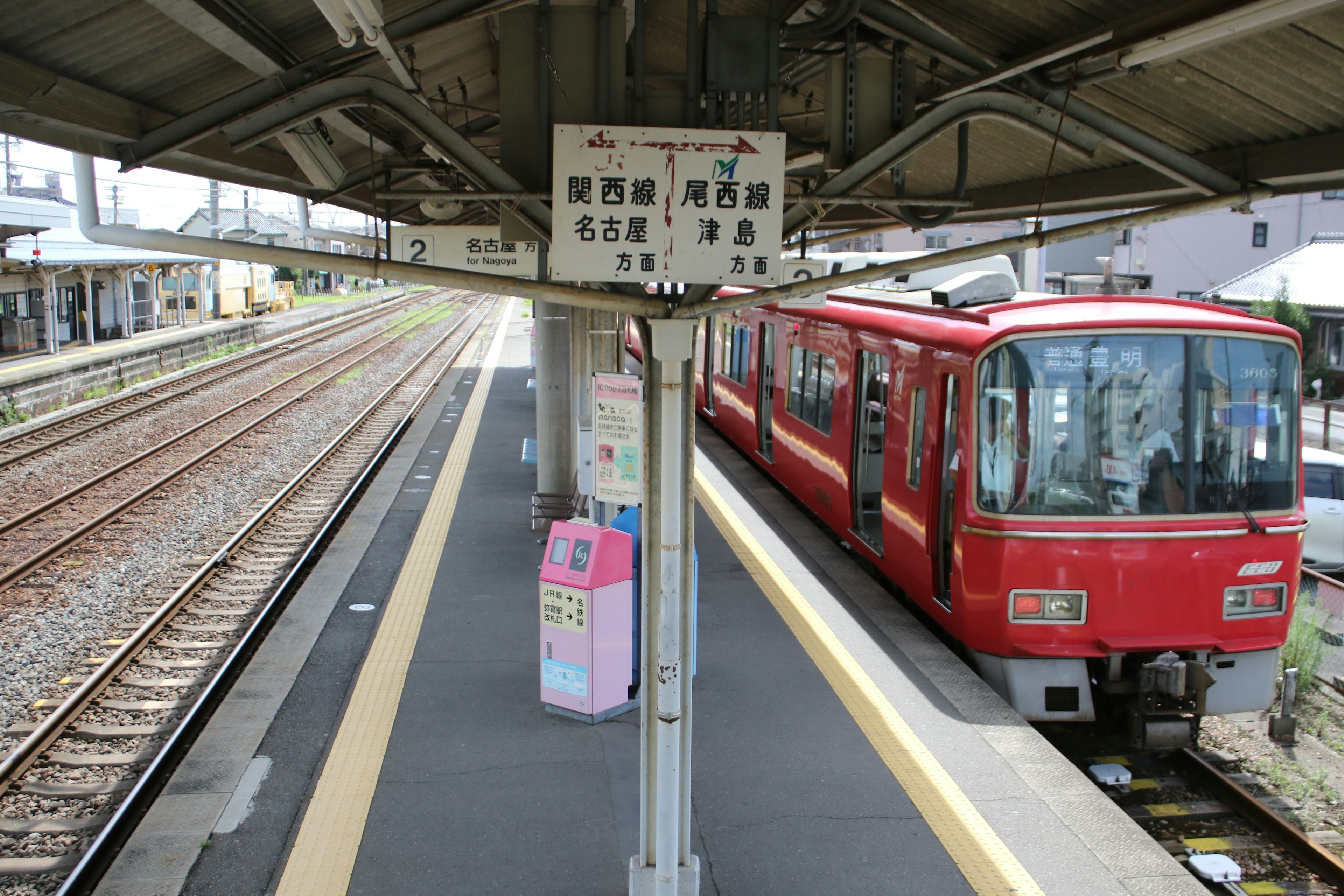 Red train at a railway station platform with signage