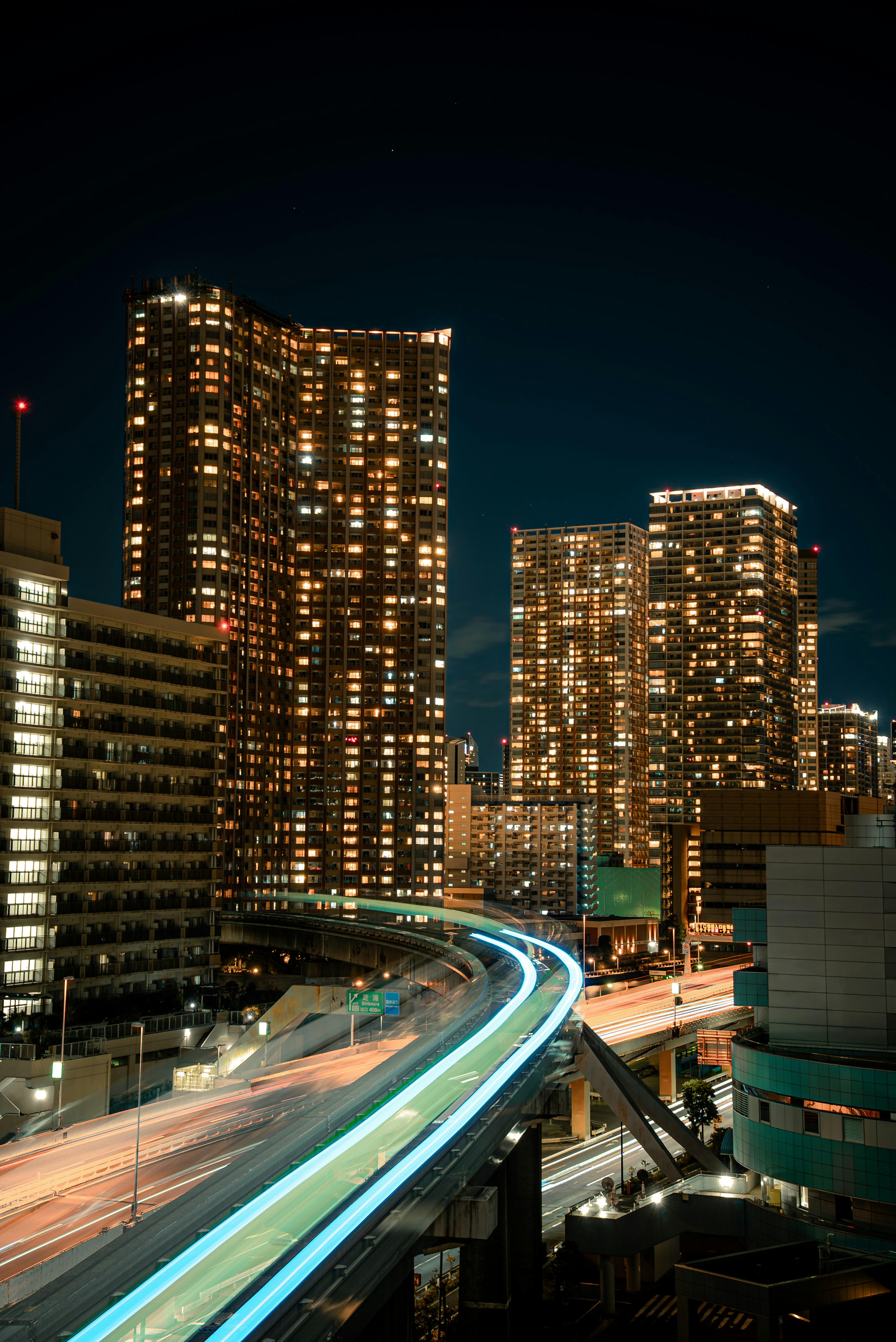 Paysage urbain nocturne avec gratte-ciels illuminés traînées lumineuses sur la route