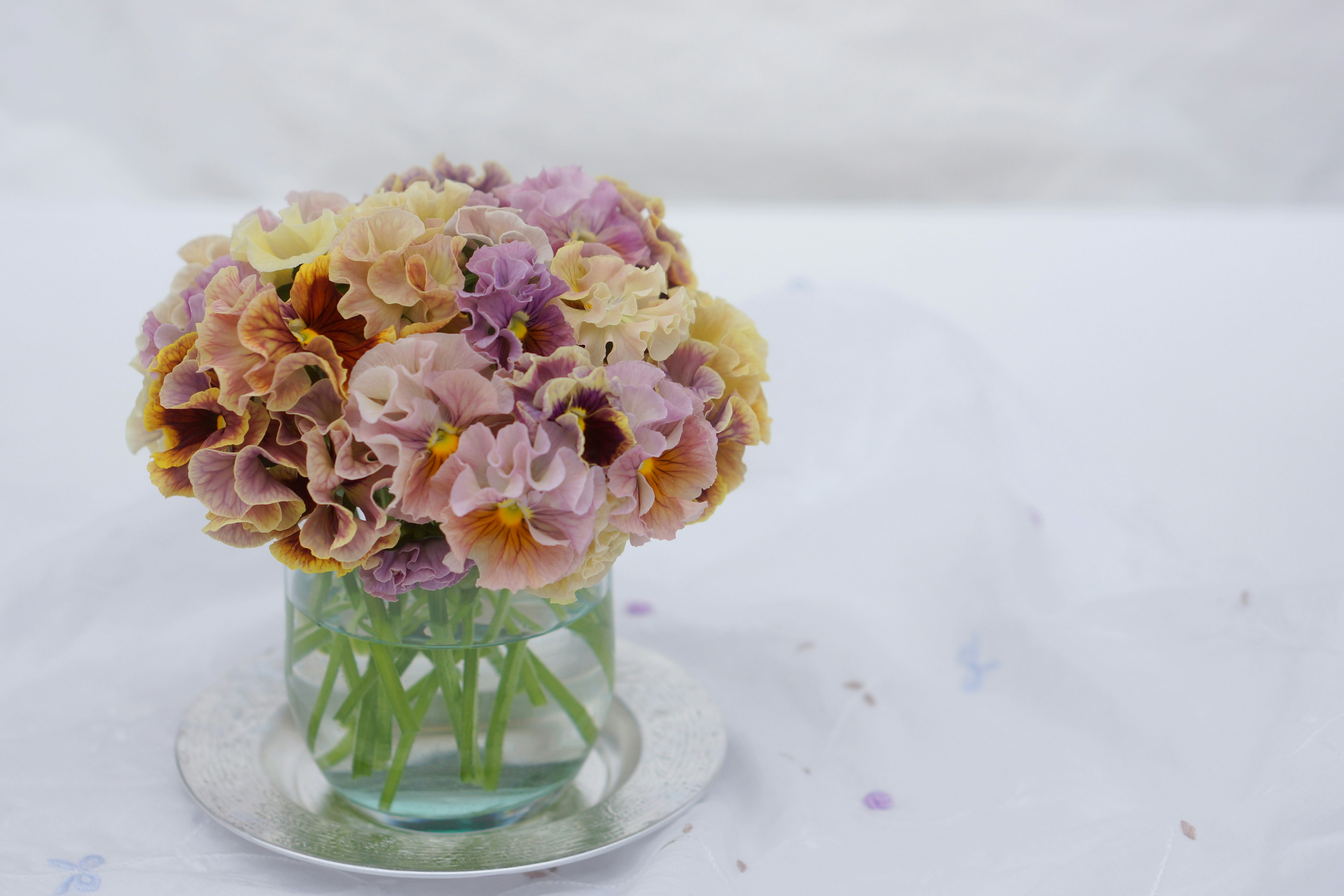 淡い色合いの花束がガラスの花瓶に入っている