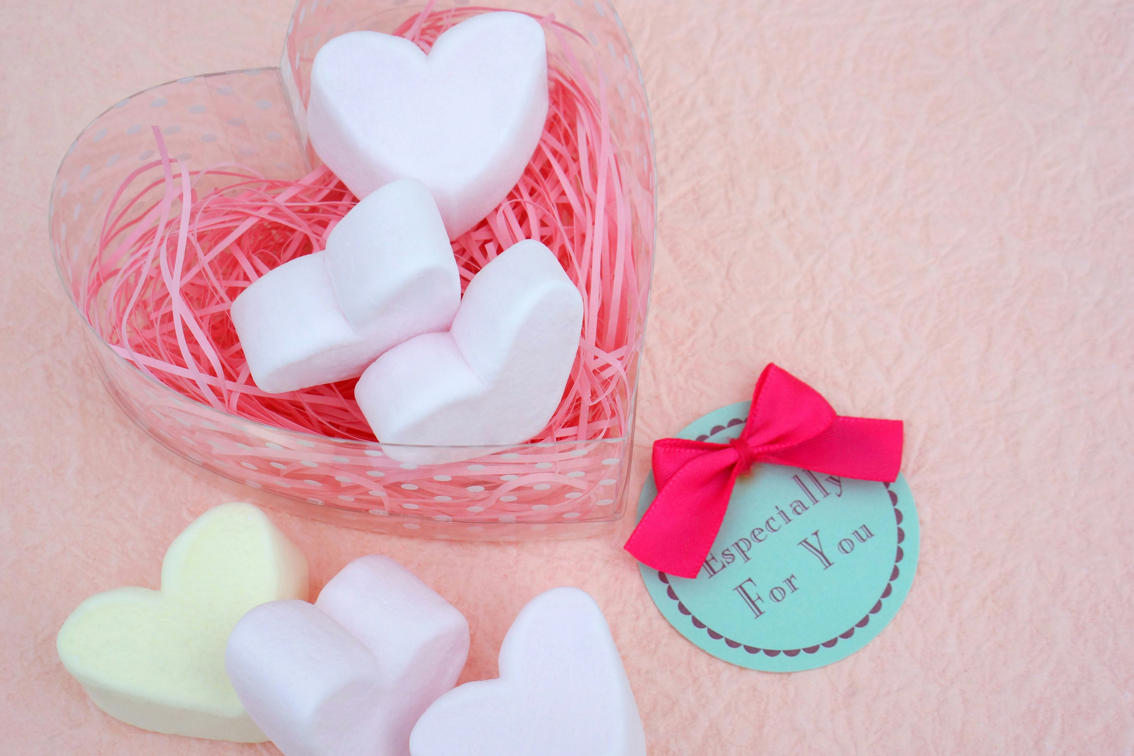 Heart-shaped candies in a transparent heart-shaped box with pink ribbon