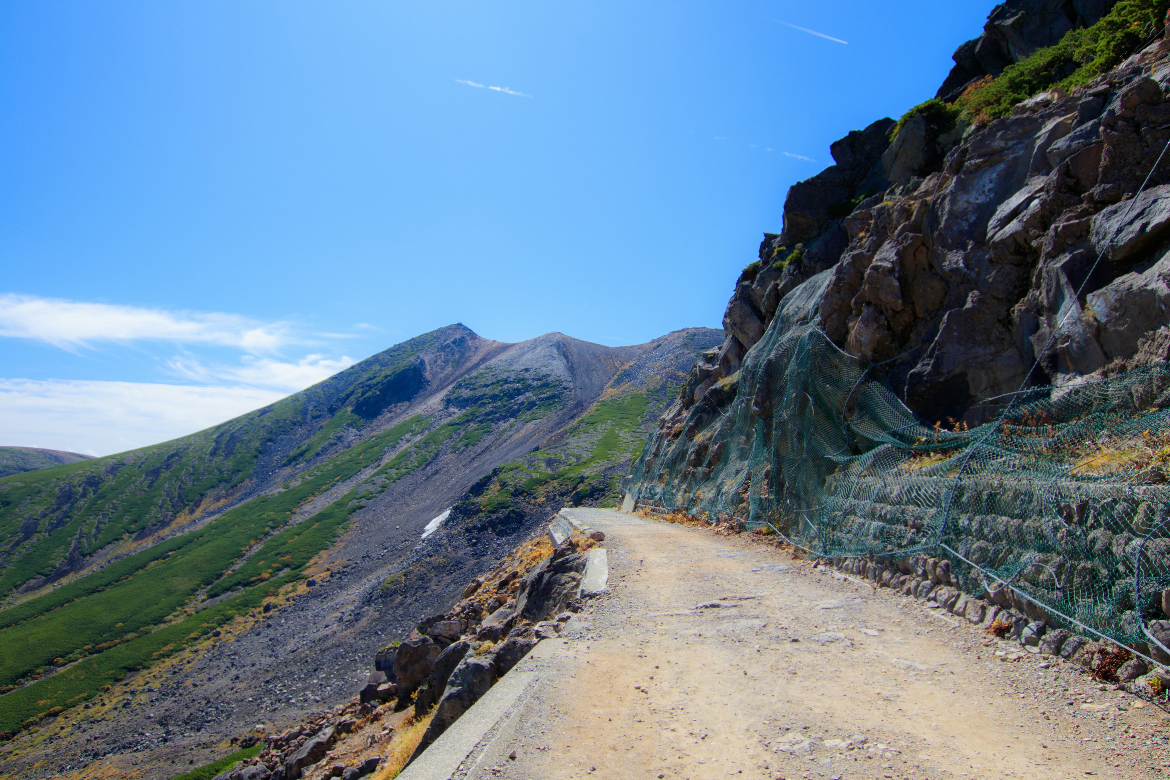 Camino de montaña pintoresco con acantilados rocosos bajo un cielo azul