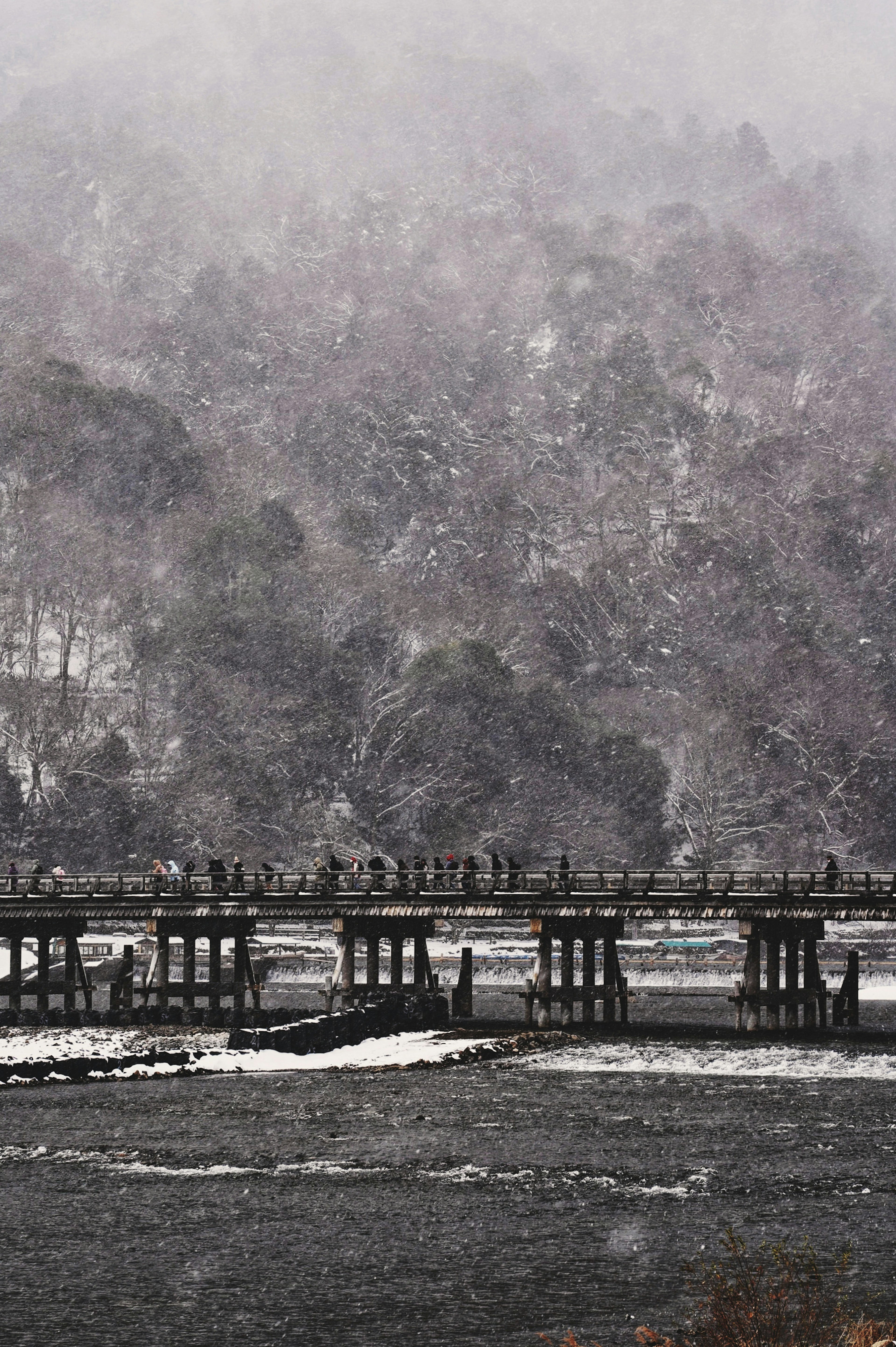 Alter Pier im Silhouette vor einer verschneiten Landschaft mit Bäumen im Hintergrund