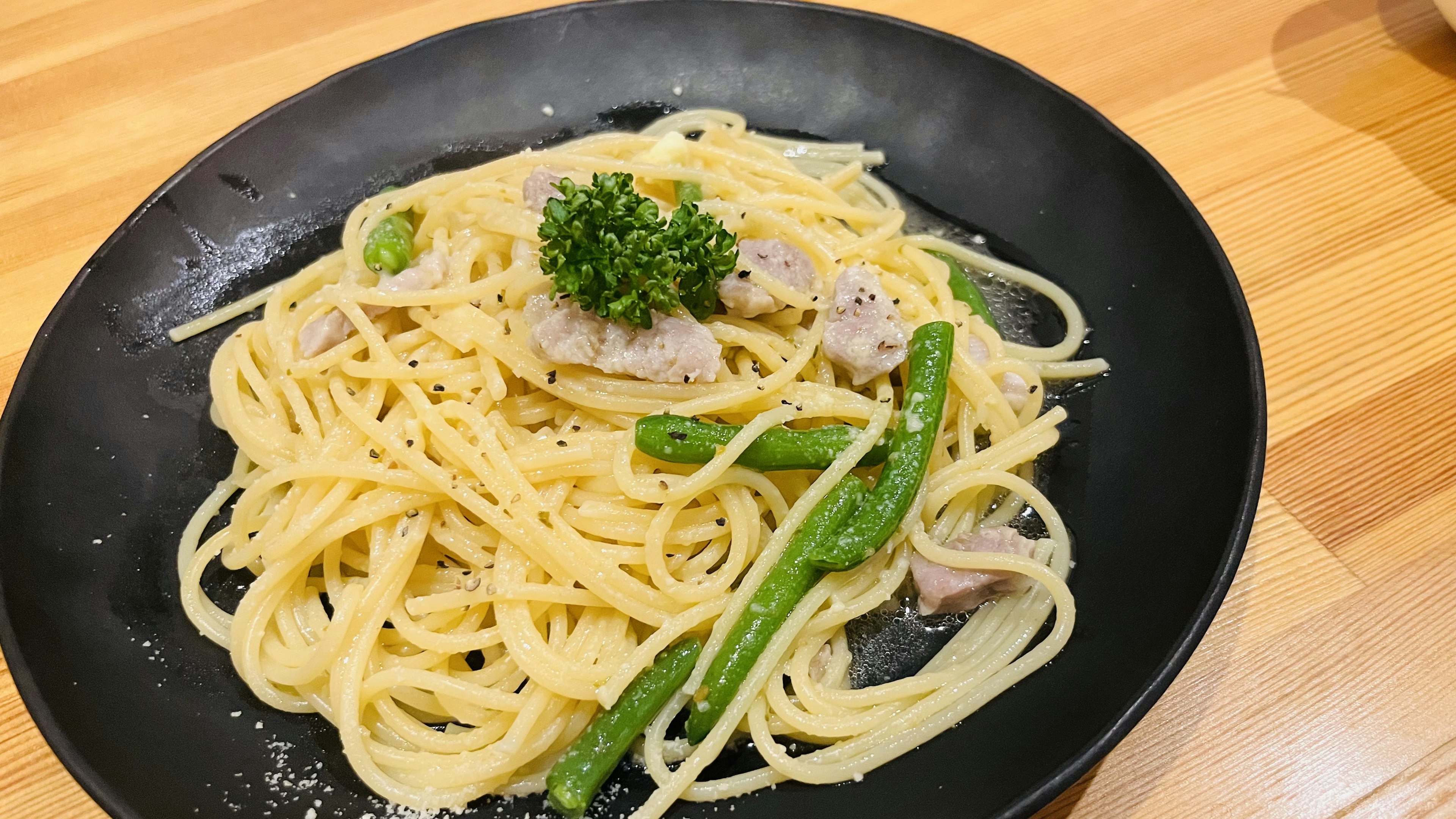 黒い皿に盛られたクリーミーなパスタとグリーンアスパラガス