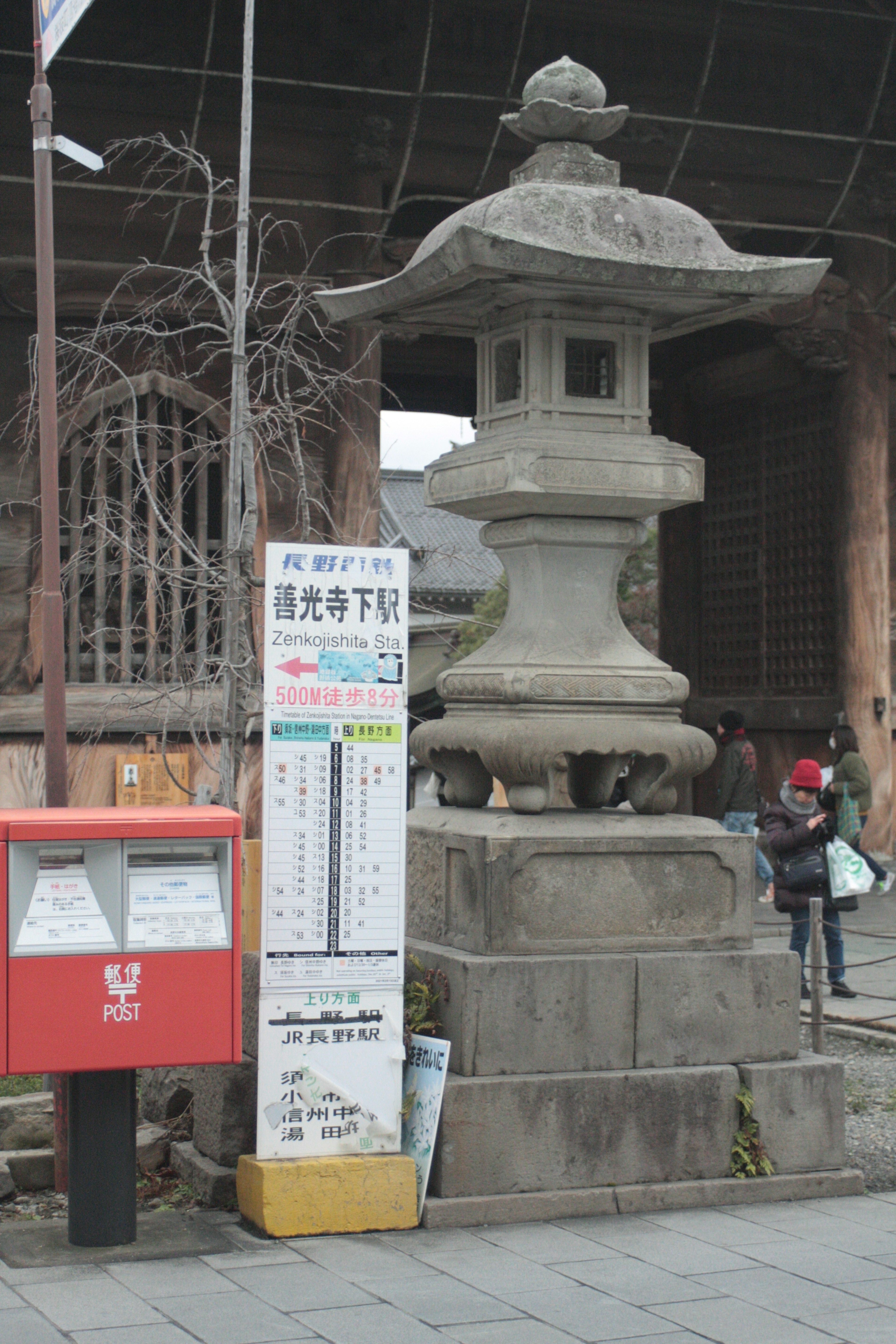 Old stone lantern next to a red mailbox