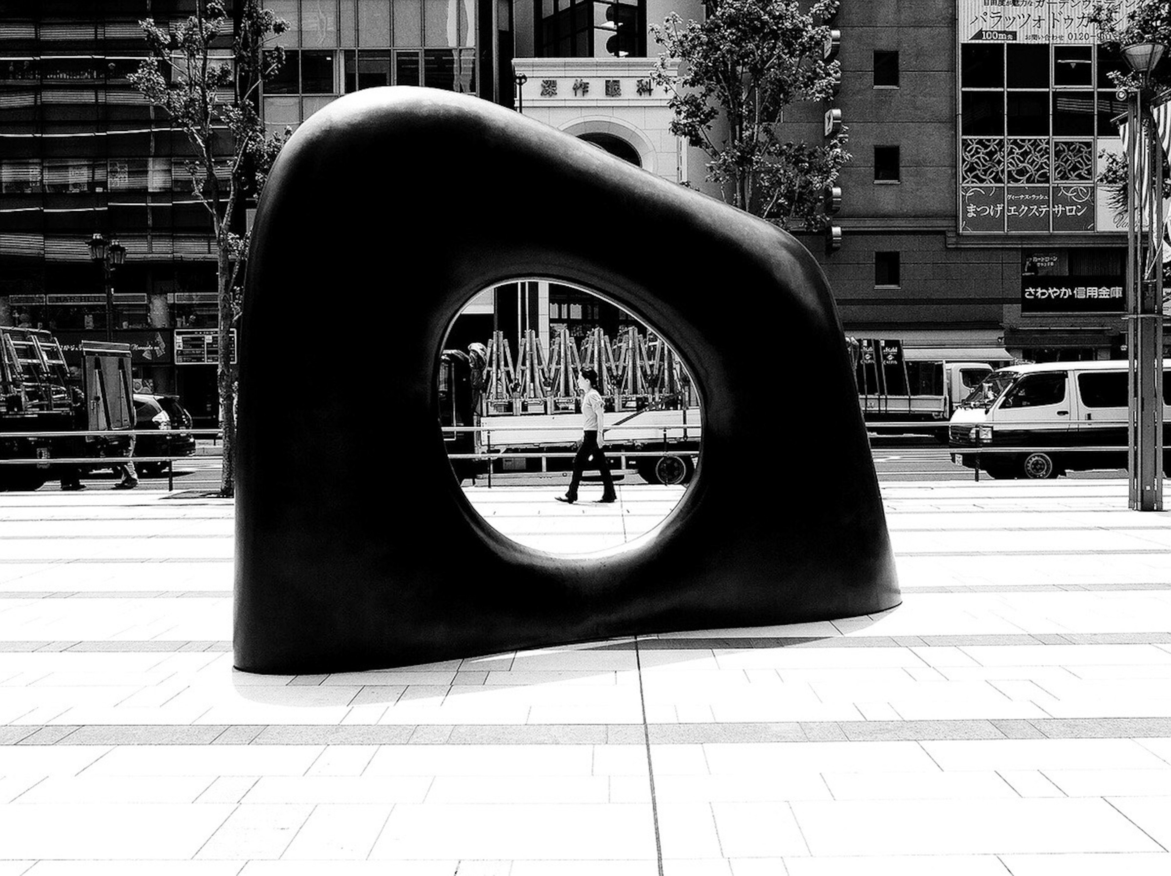 Escultura negra con una abertura circular en una calle de la ciudad