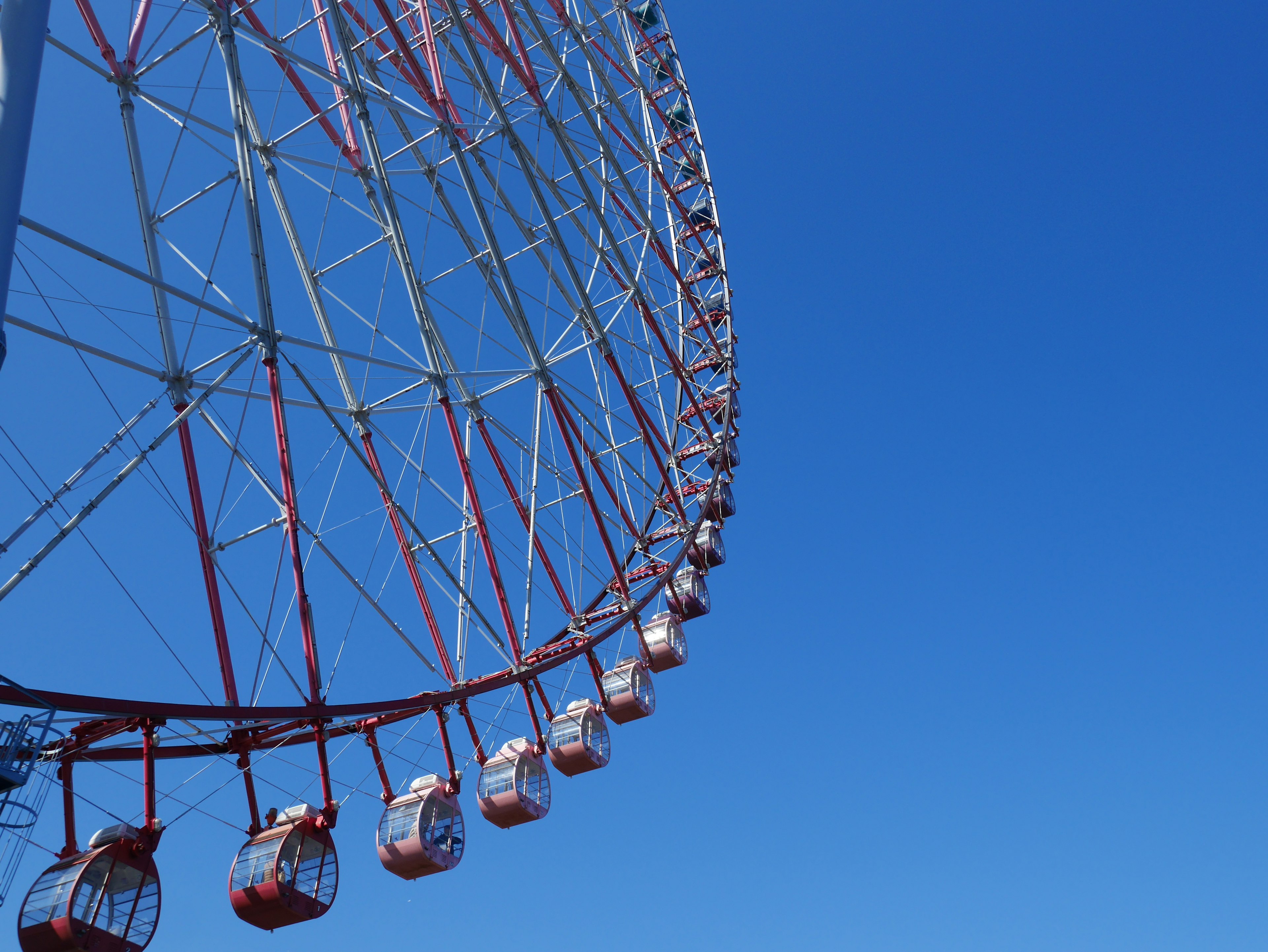 Part of a Ferris wheel with colorful gondolas against a blue sky