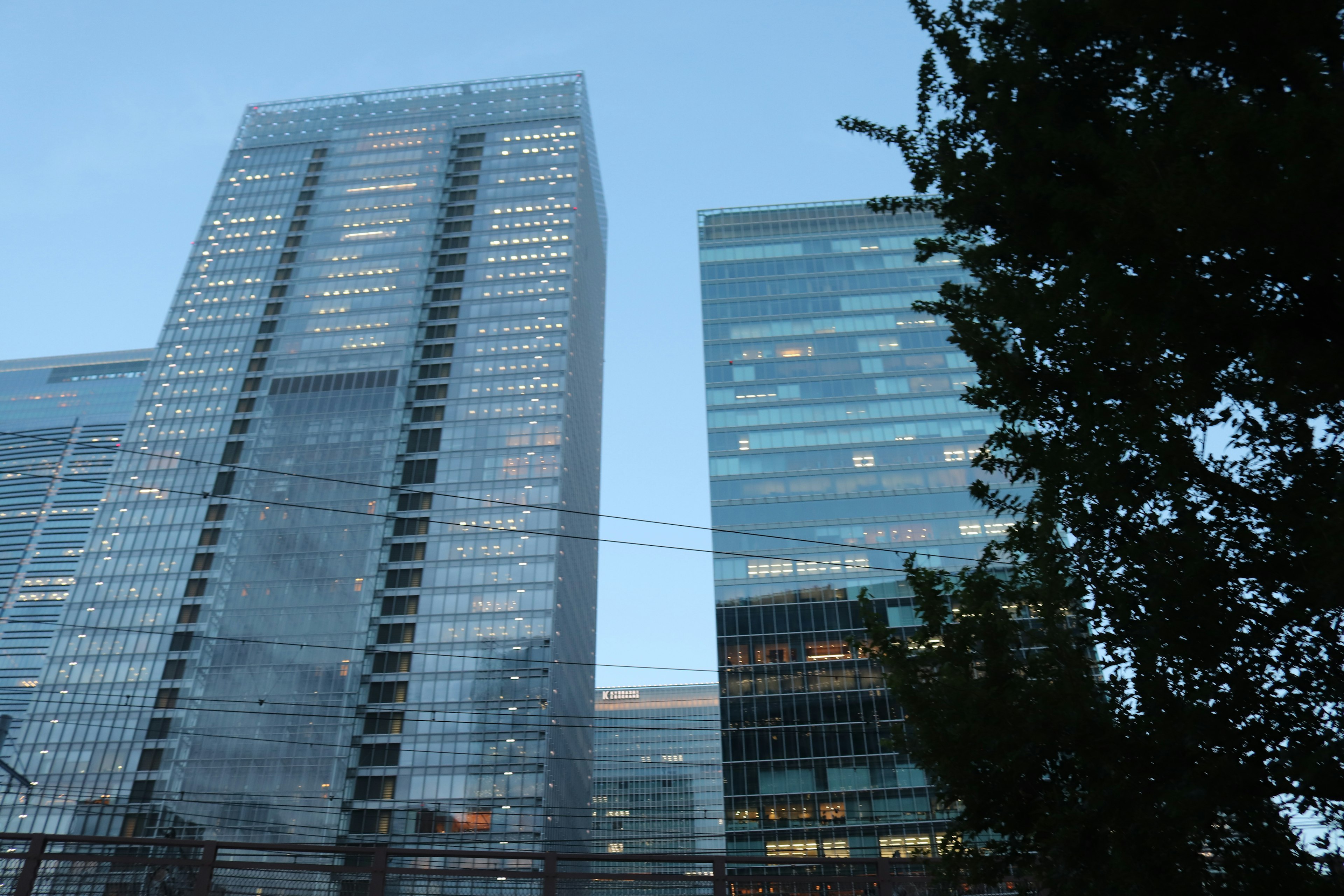 Skyline featuring tall glass buildings against a blue sky with greenery