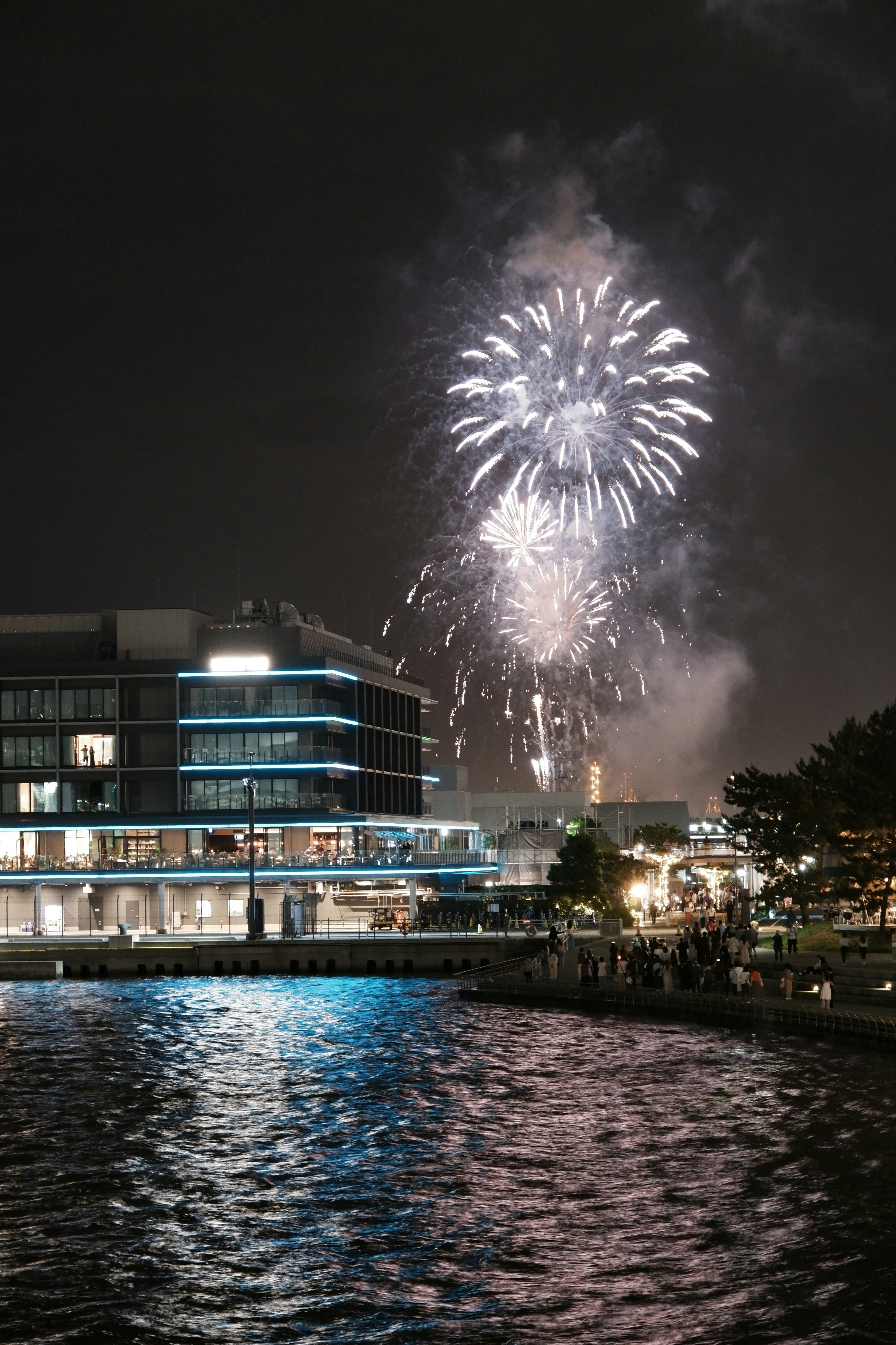 Fireworks explode in the night sky reflecting on the water surface