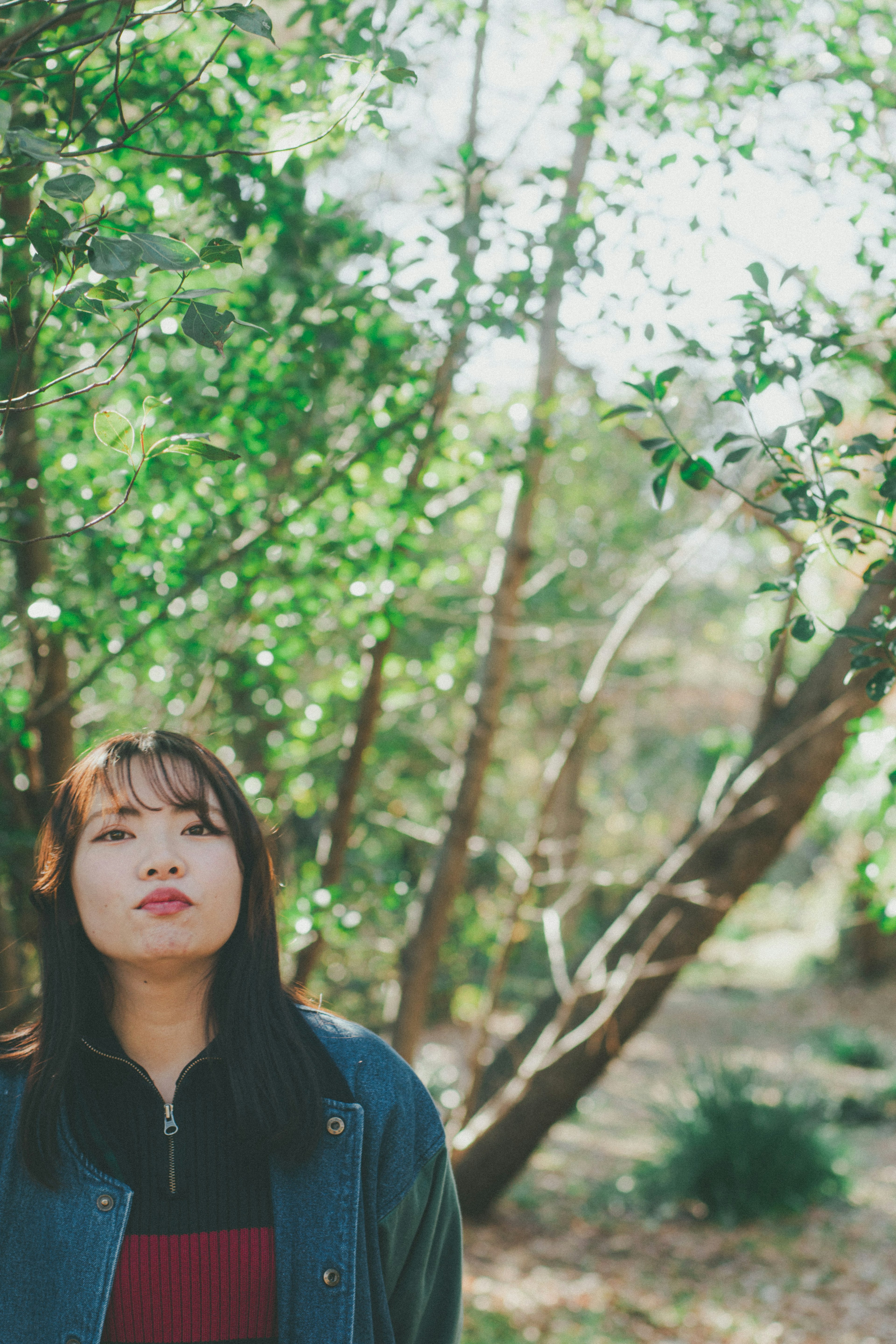 Portrait d'une femme réfléchissant parmi des arbres verts