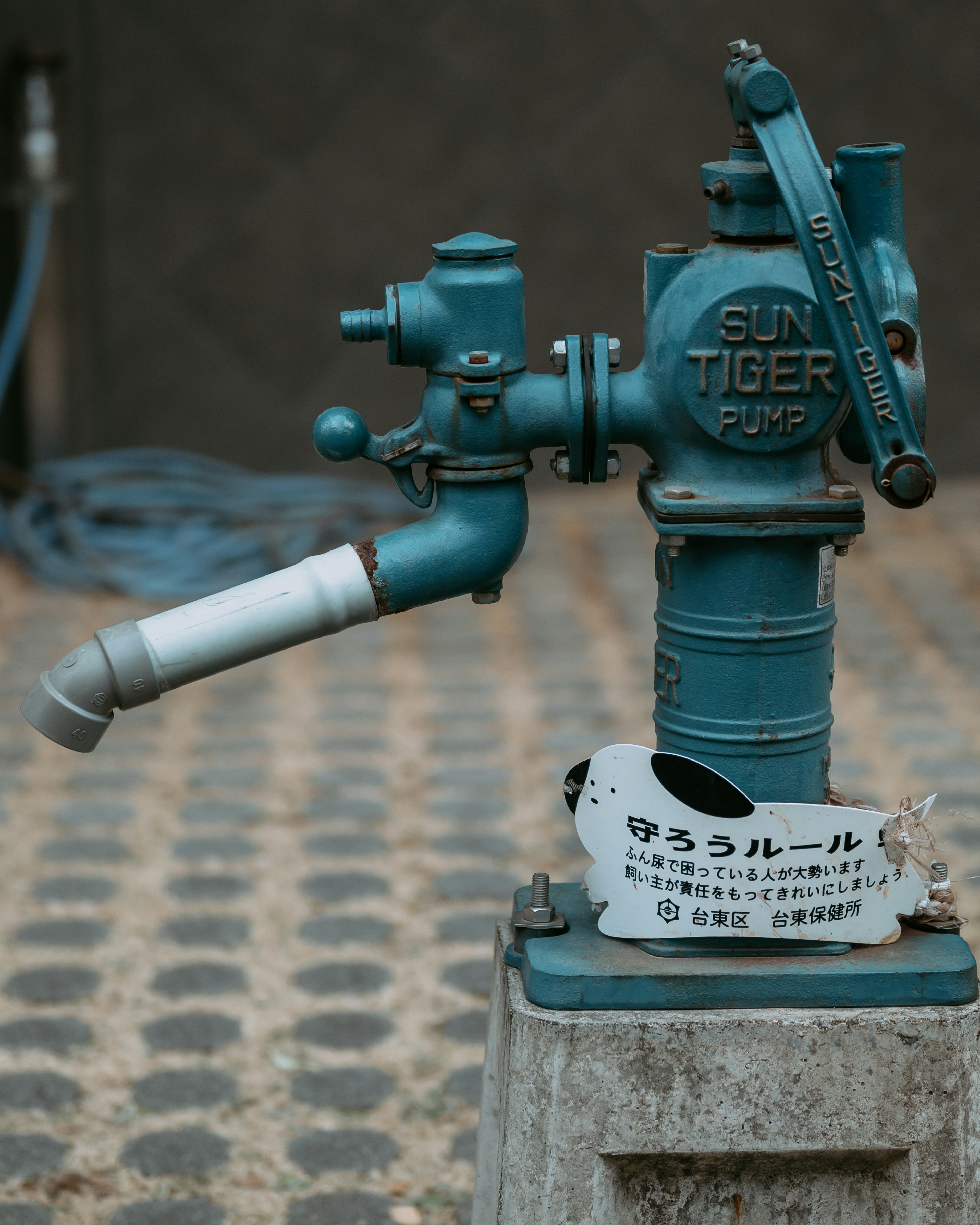 Blue water pump with a unique design and cobblestone pattern background