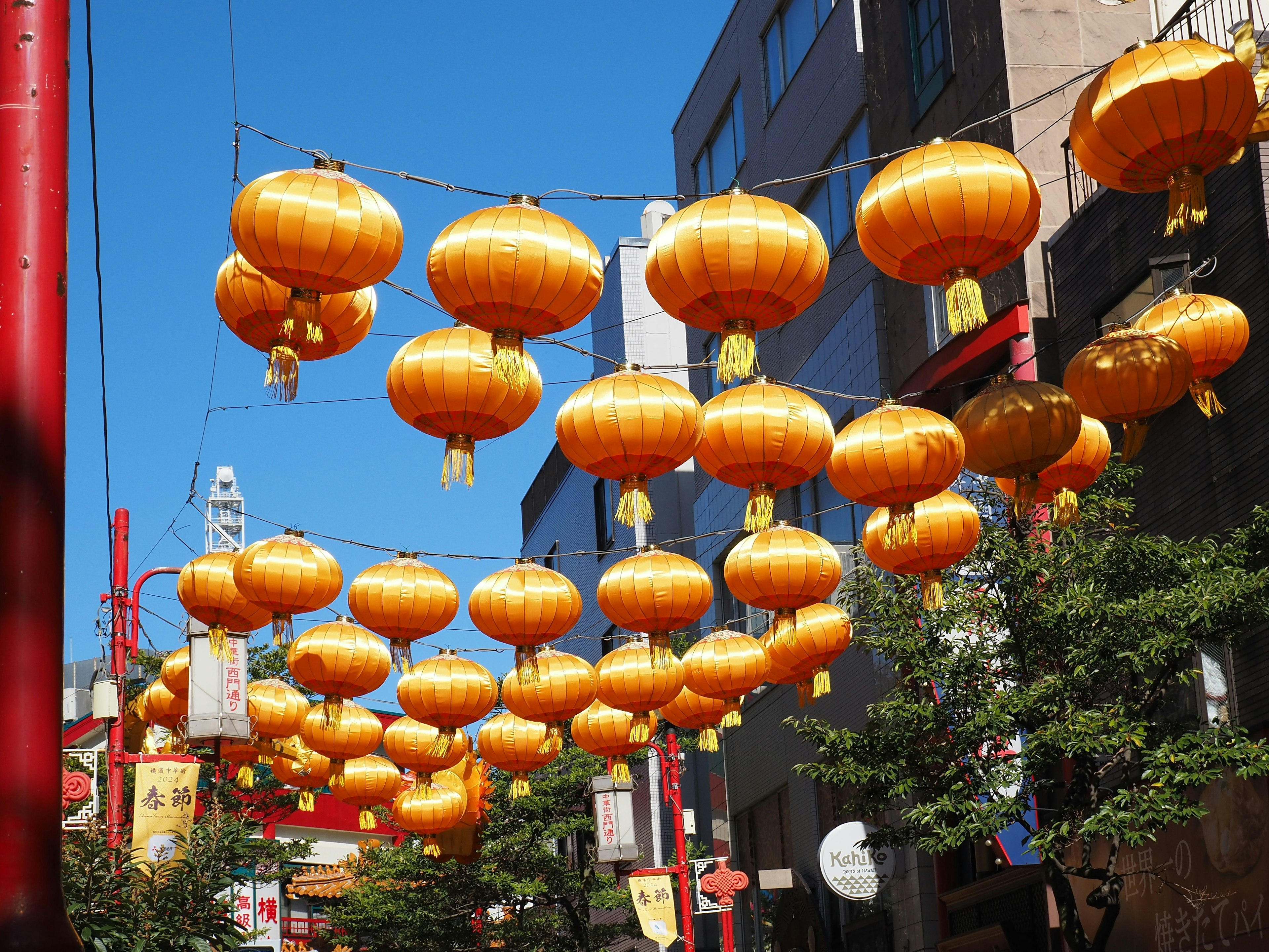 Una calle decorada con faroles dorados colgando bajo un cielo azul