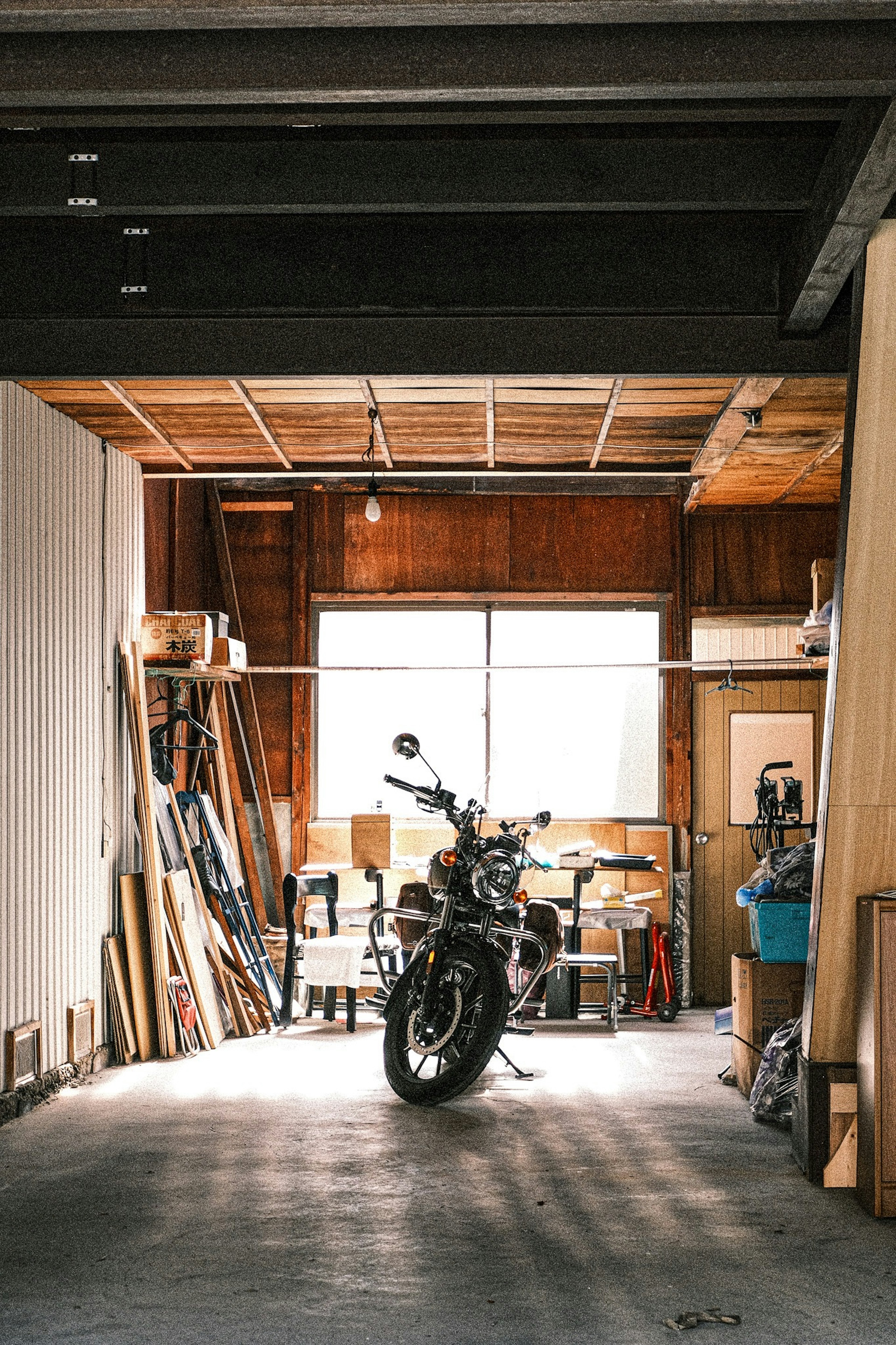 Moto garée dans un garage en bois avec divers outils et bois