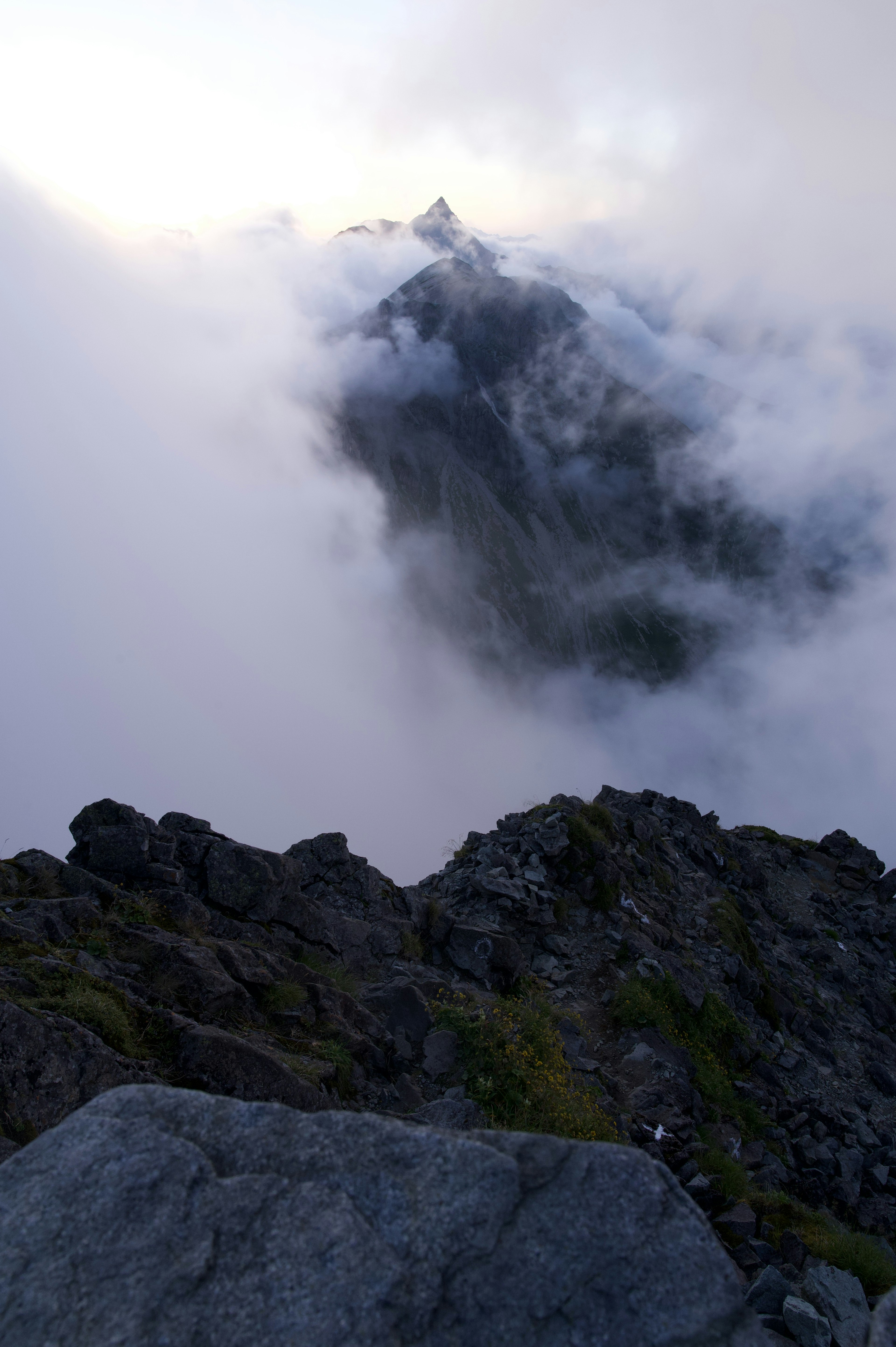 Mountain landscape shrouded in mist with rocky foreground