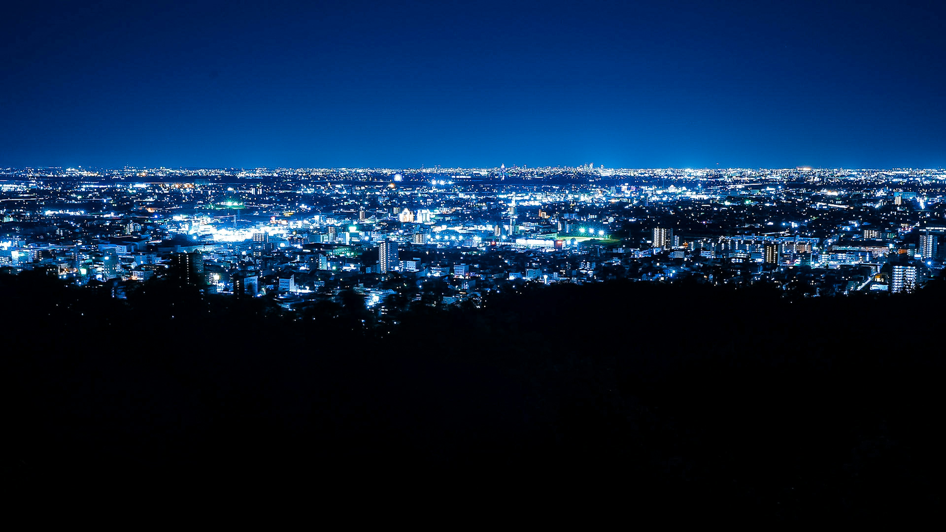 Paisaje urbano nocturno con luces brillantes y cielo azul profundo