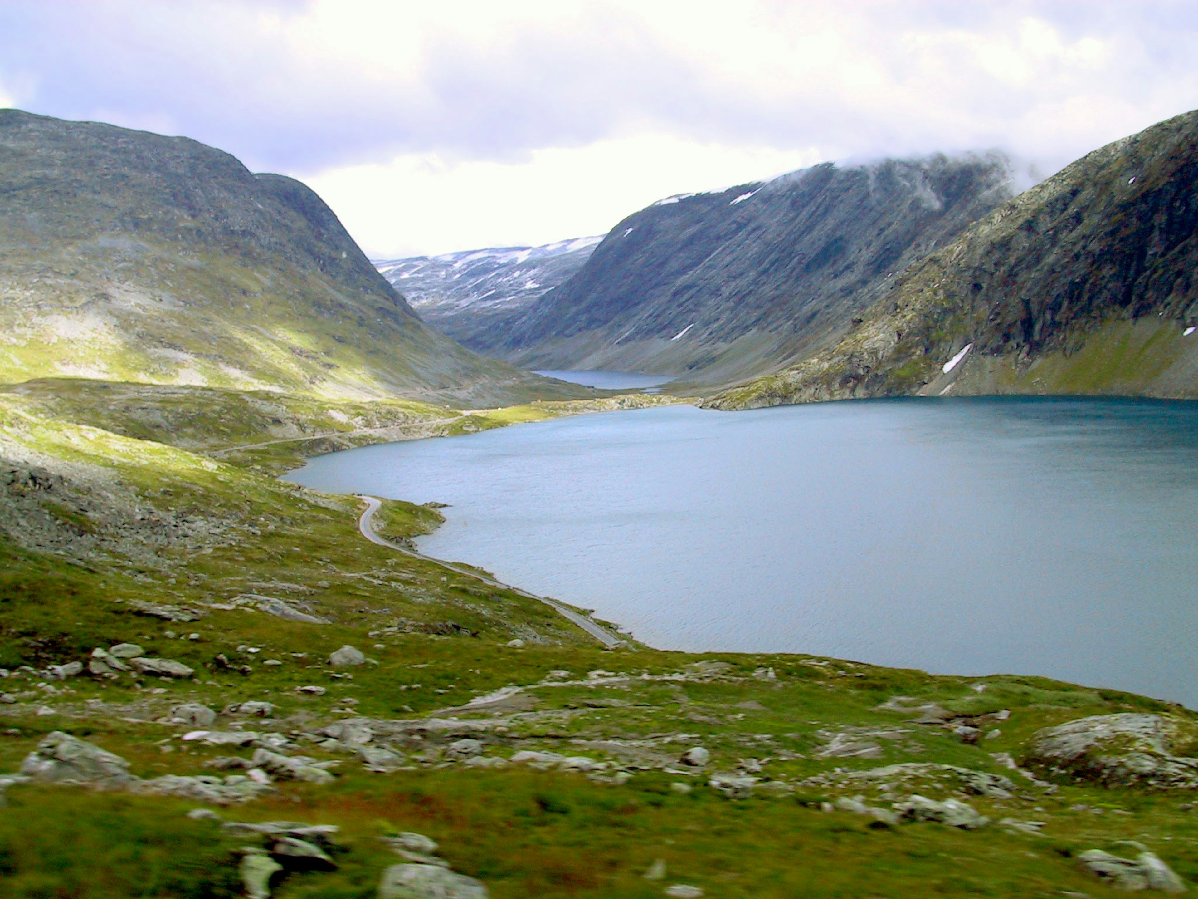 Malerischer See umgeben von majestätischen Bergen und Grünflächen