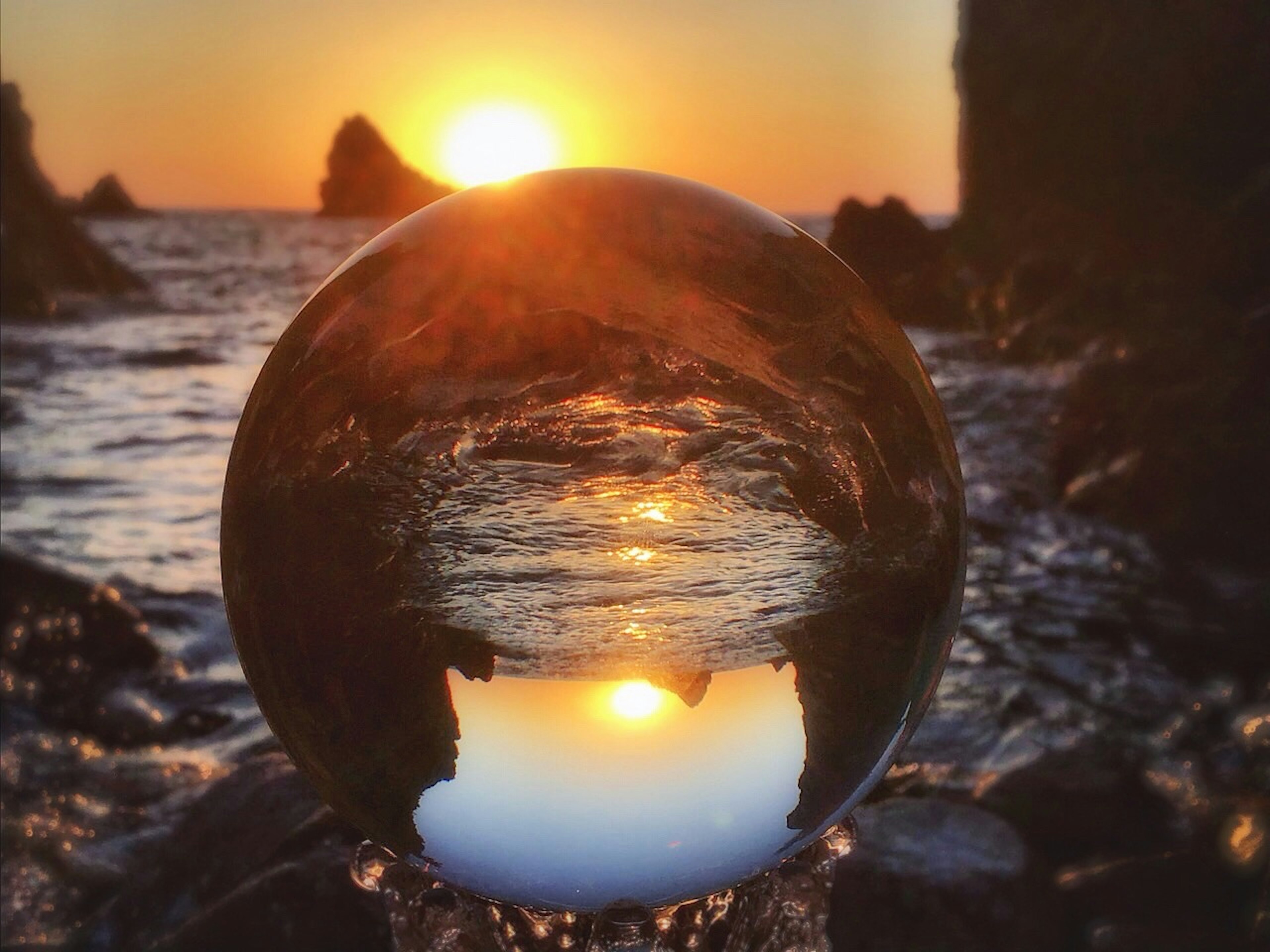 海岸沿いの夕日を映した透明なクリスタルボール