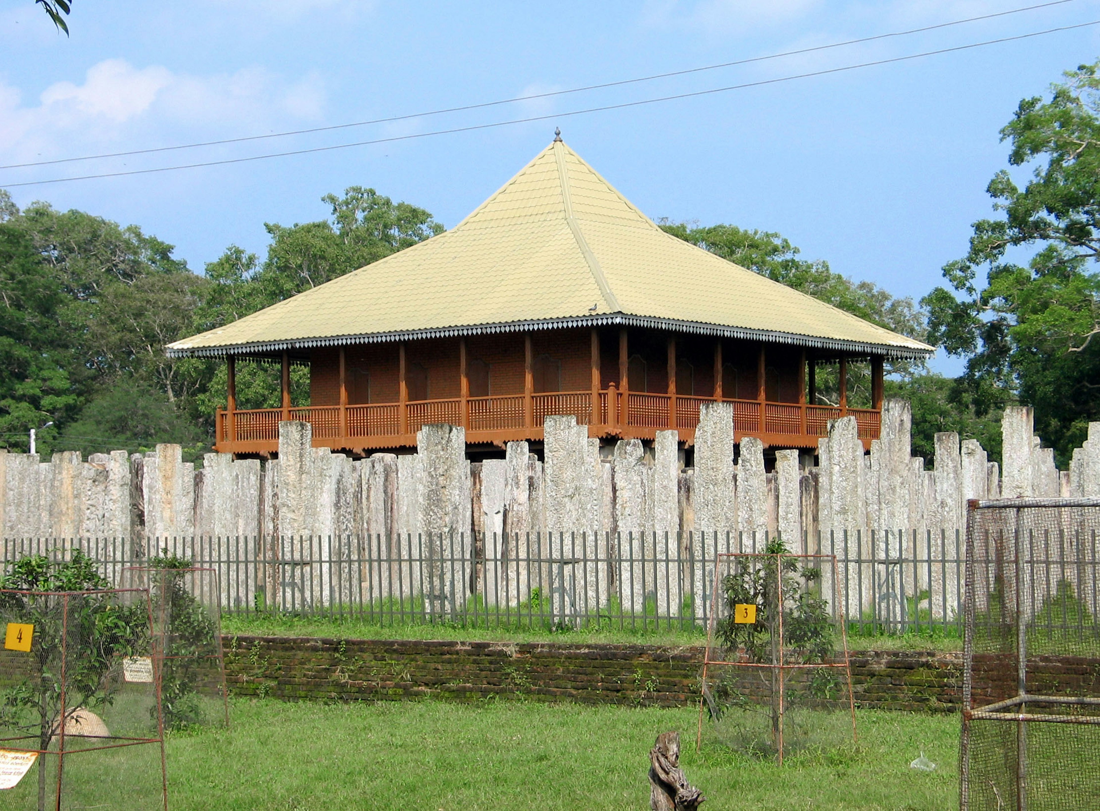 Bangunan tradisional dengan atap khas dikelilingi tiang batu