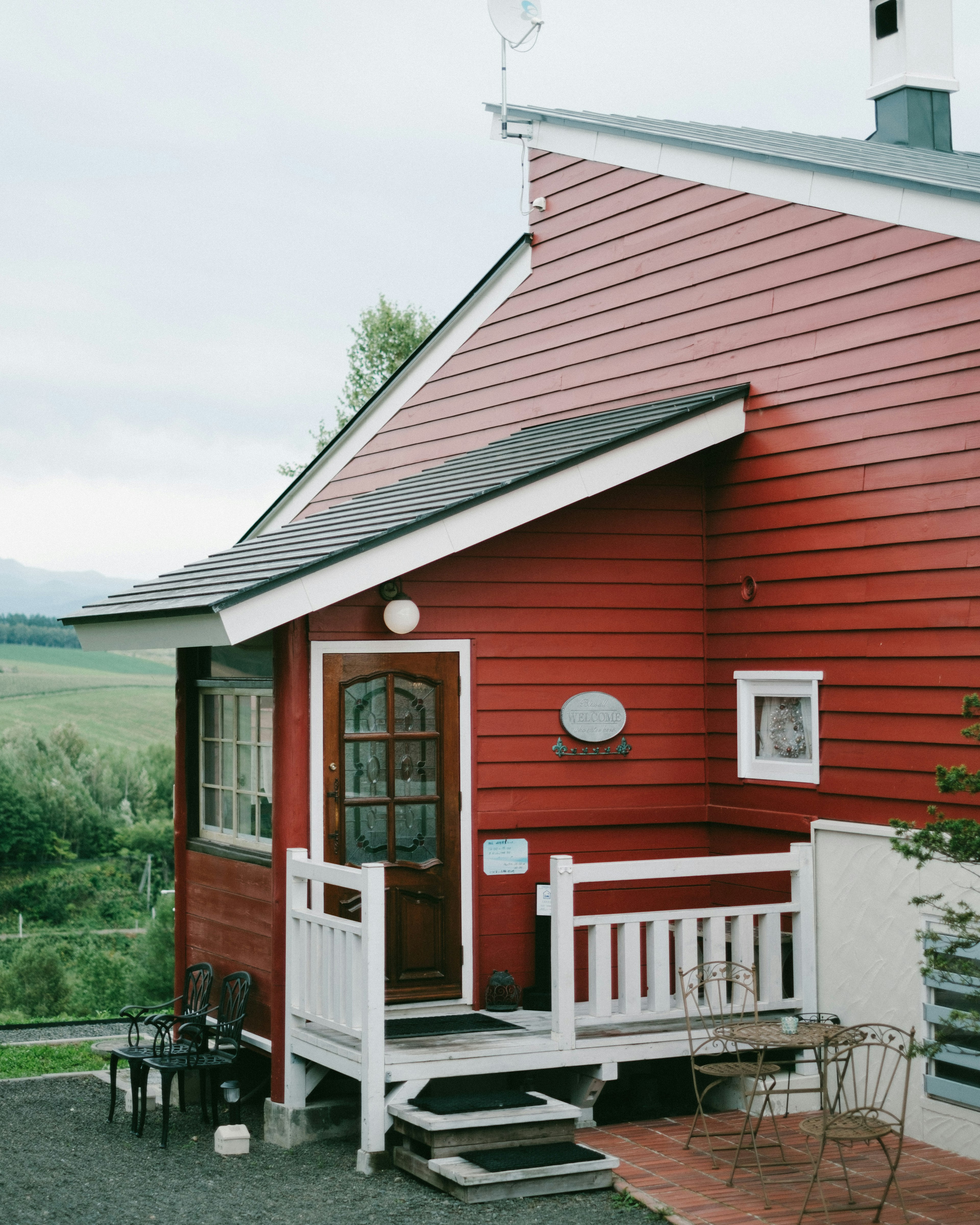 Red exterior house with a porch and garden view