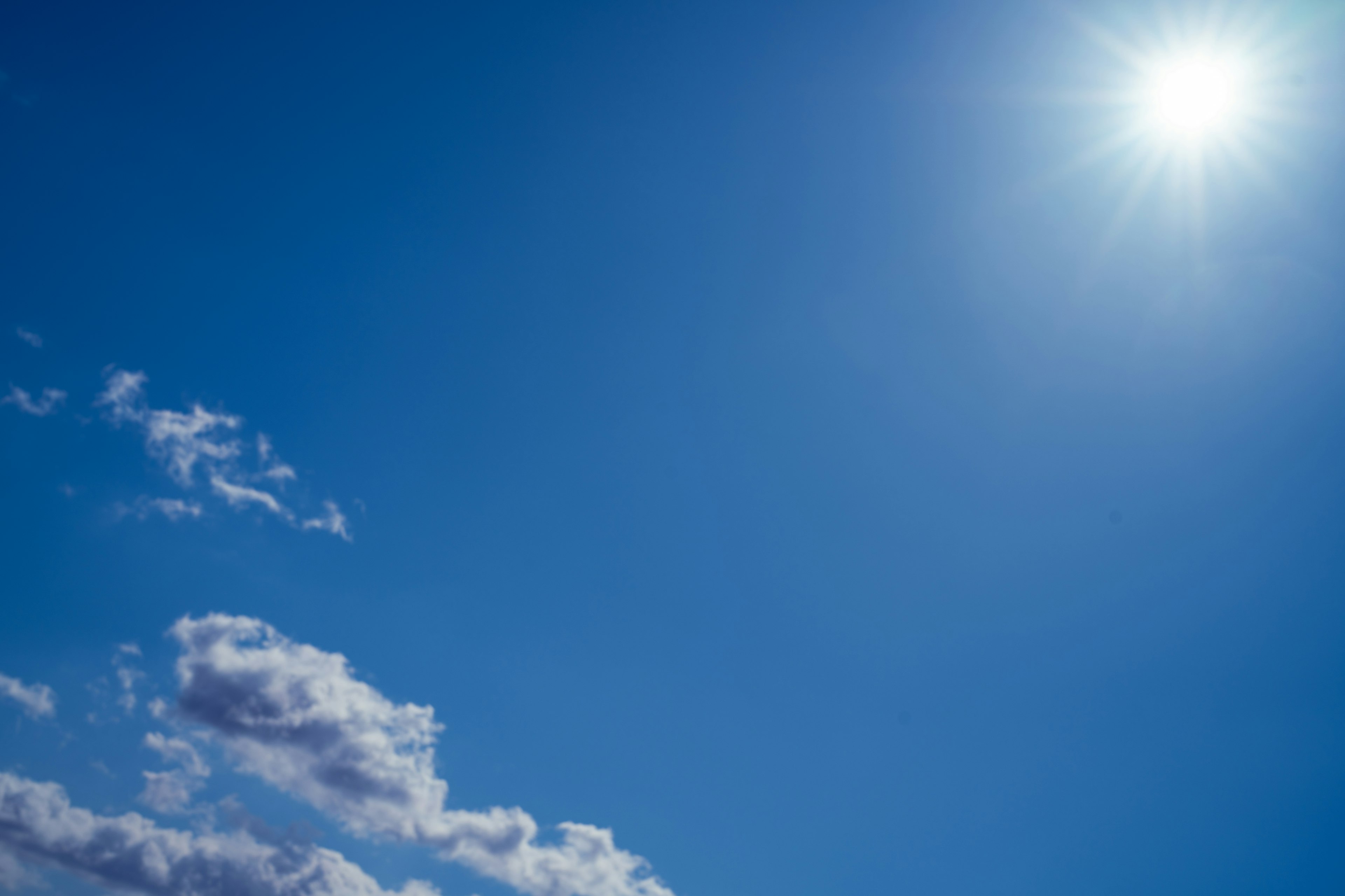 Heller blauer Himmel mit weißen Wolken und strahlender Sonne