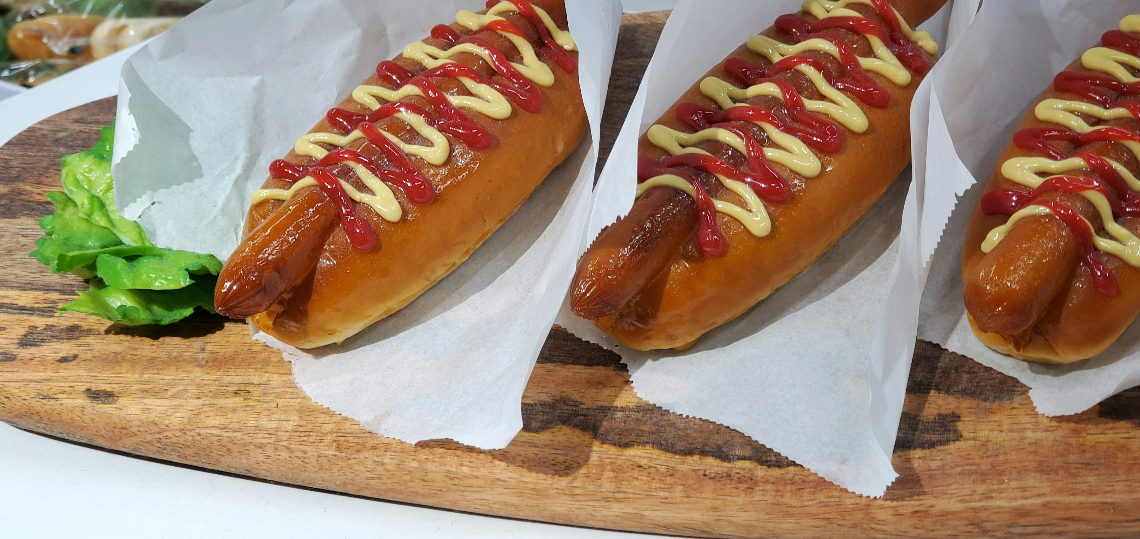 Three hot dogs arranged on a wooden board