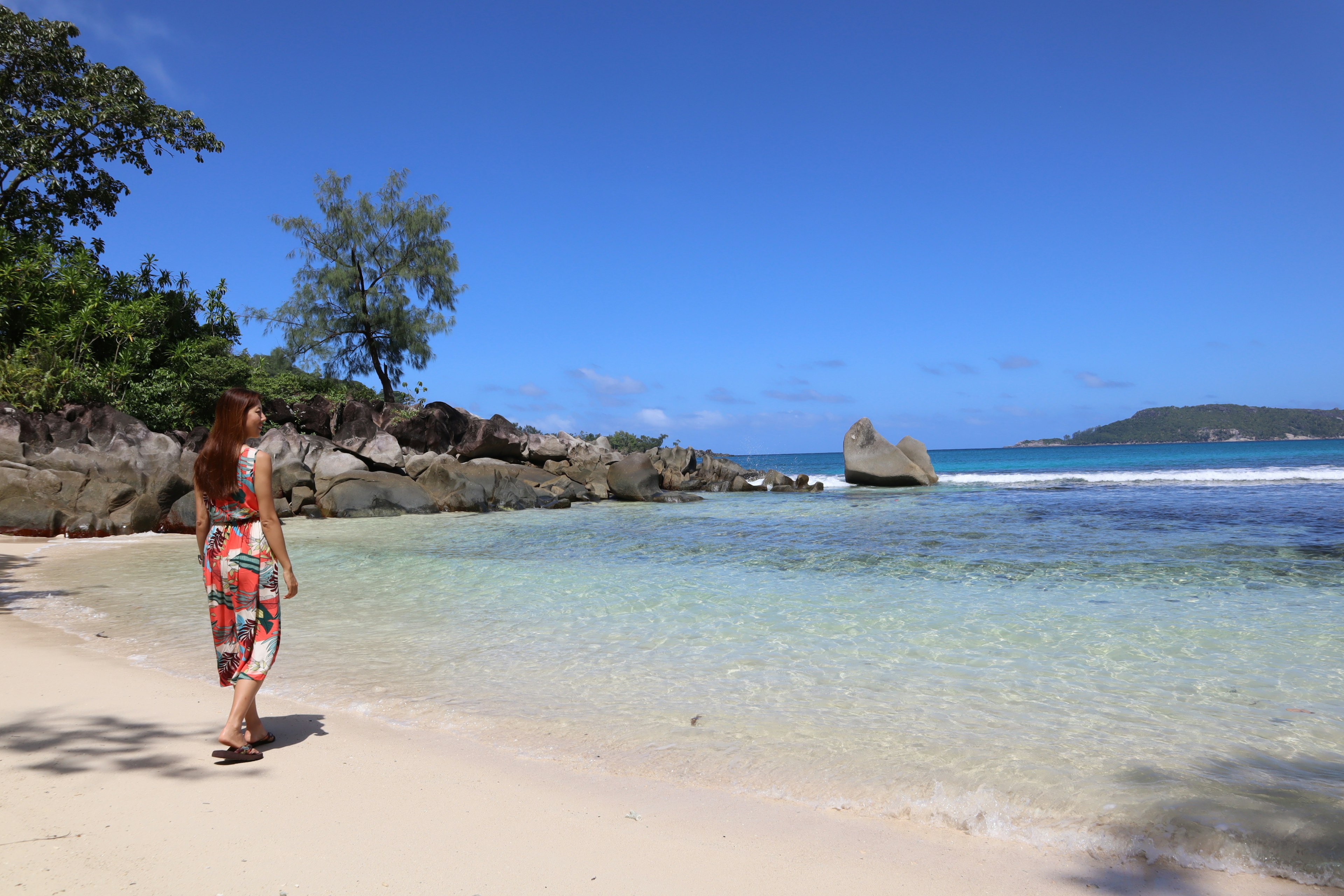 Woman walking on a beautiful beach with clear blue sky and calm sea