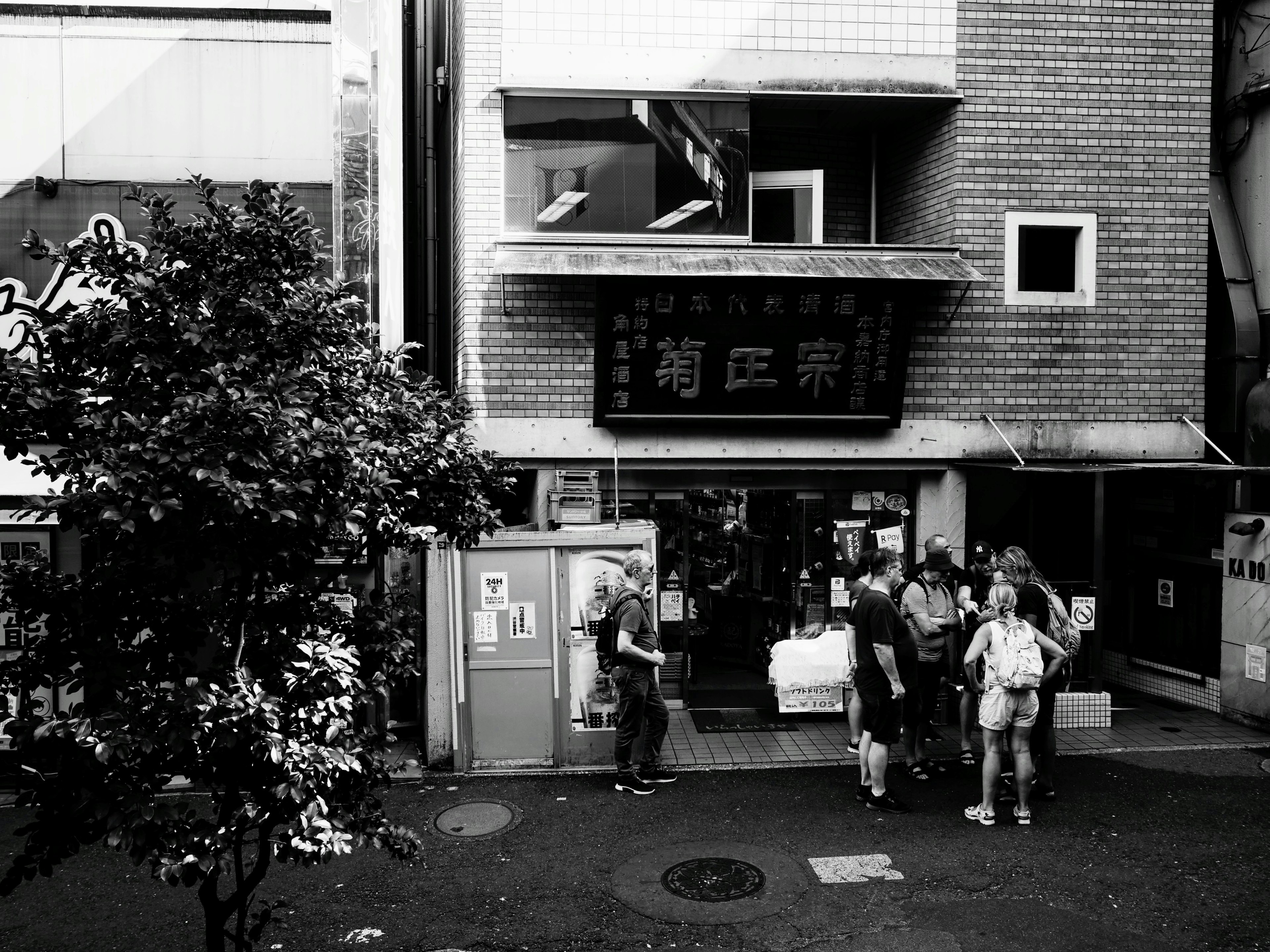 Black and white street scene with people gathered in front of a restaurant