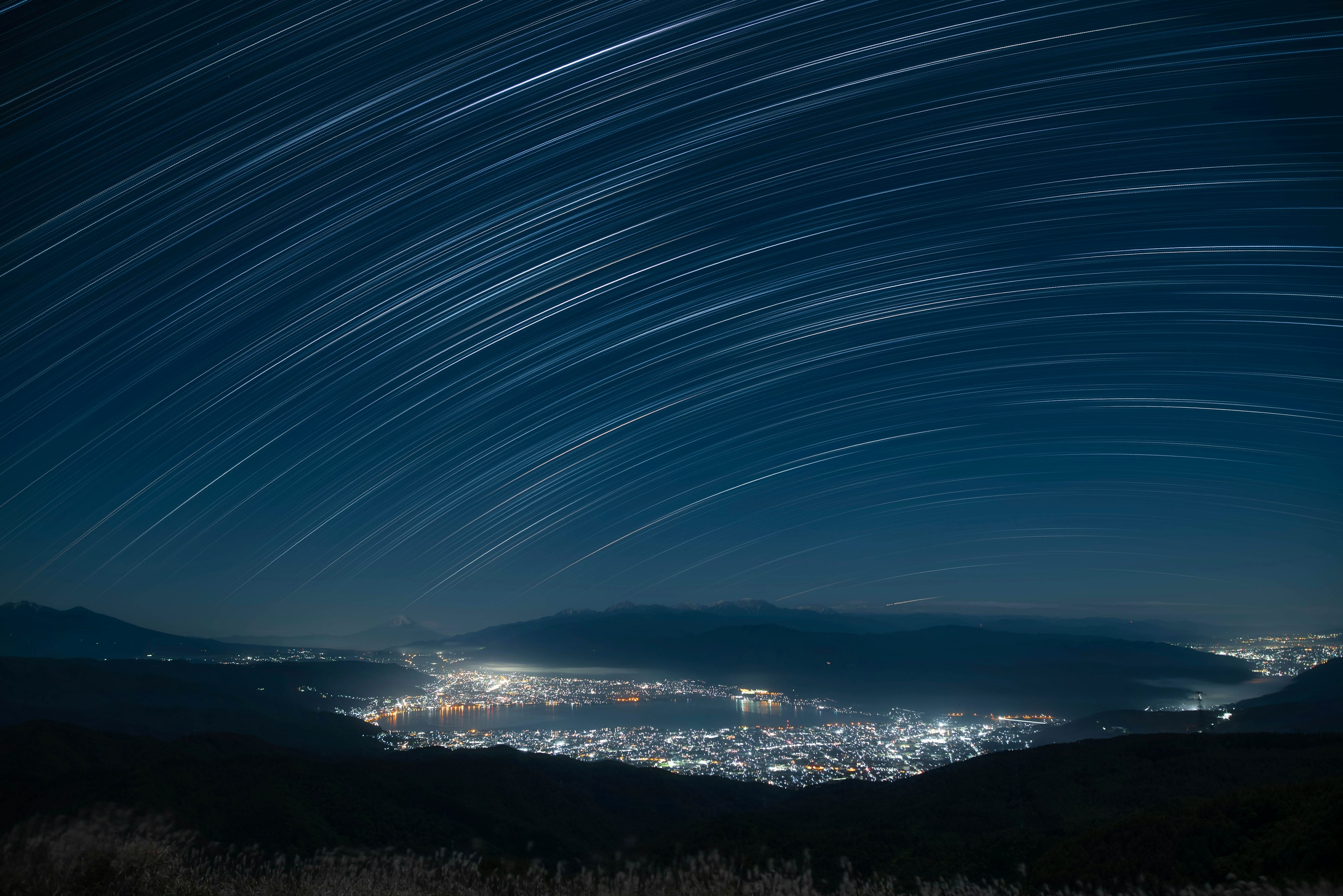 星の軌跡が映る夜空の風景と都市の明かり