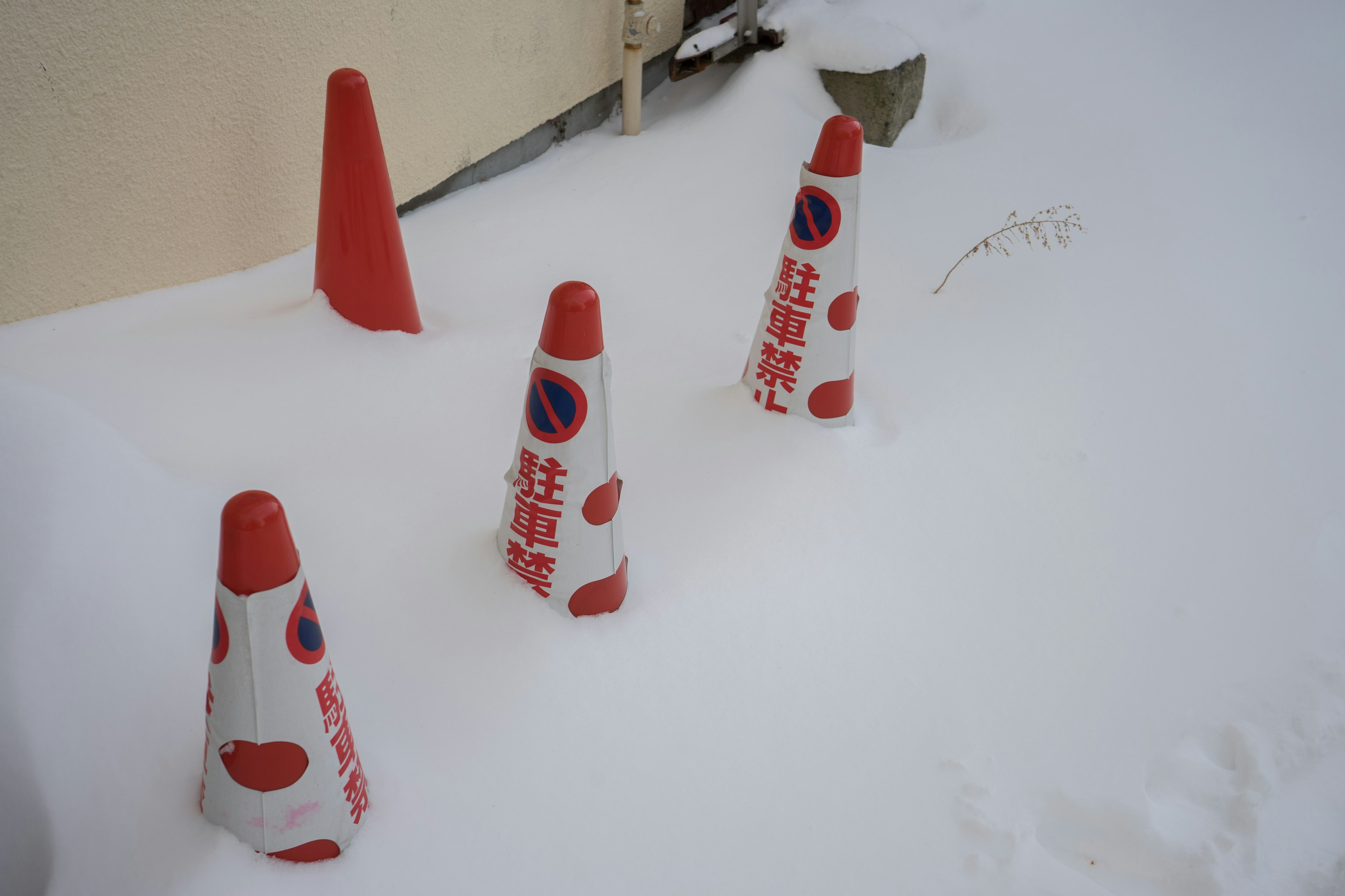 Coni stradali coperti di neve con design rosso e bianco e segnali di divieto di sosta