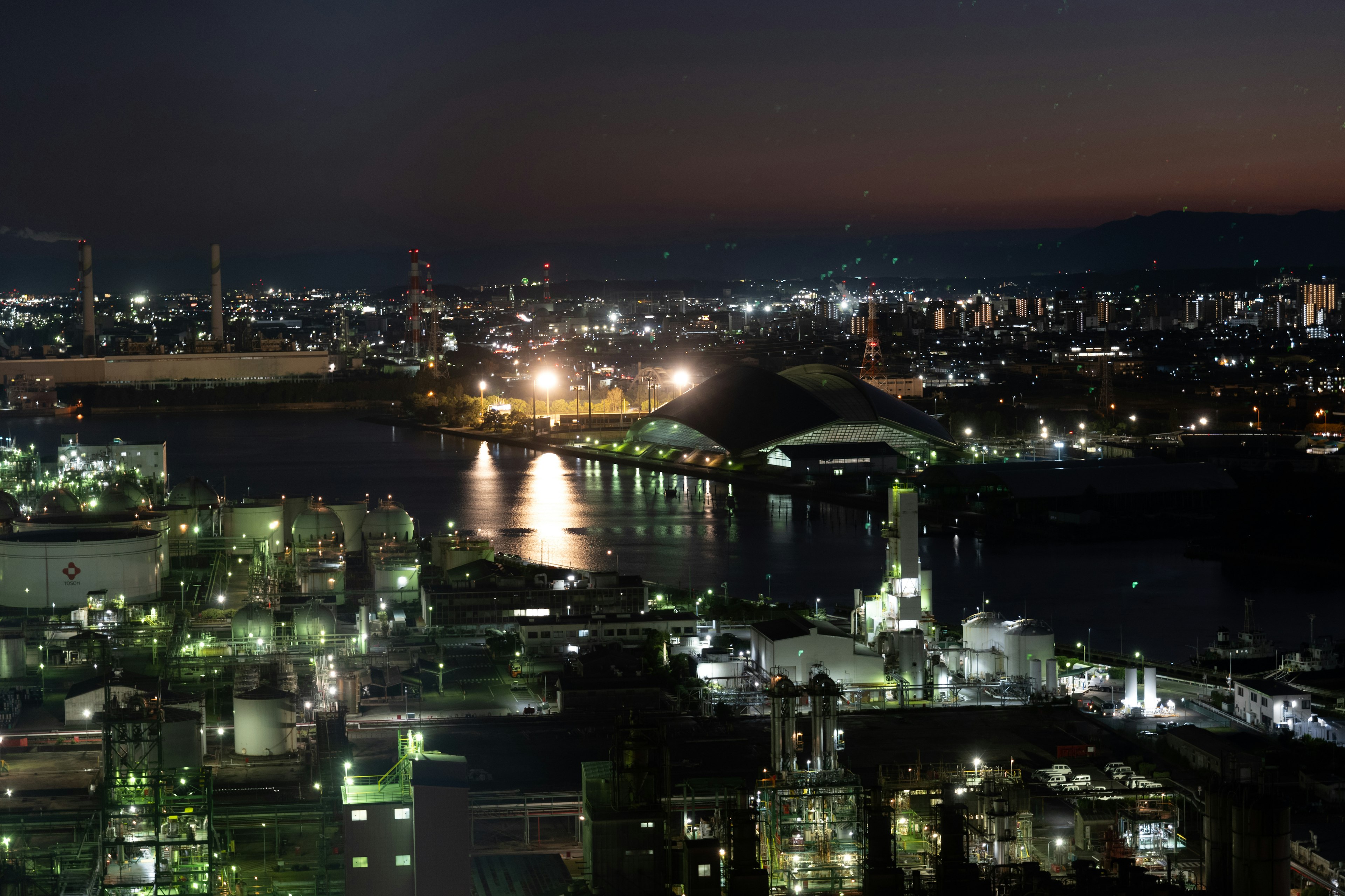 Vue nocturne d'une zone industrielle avec port et bâtiments illuminés