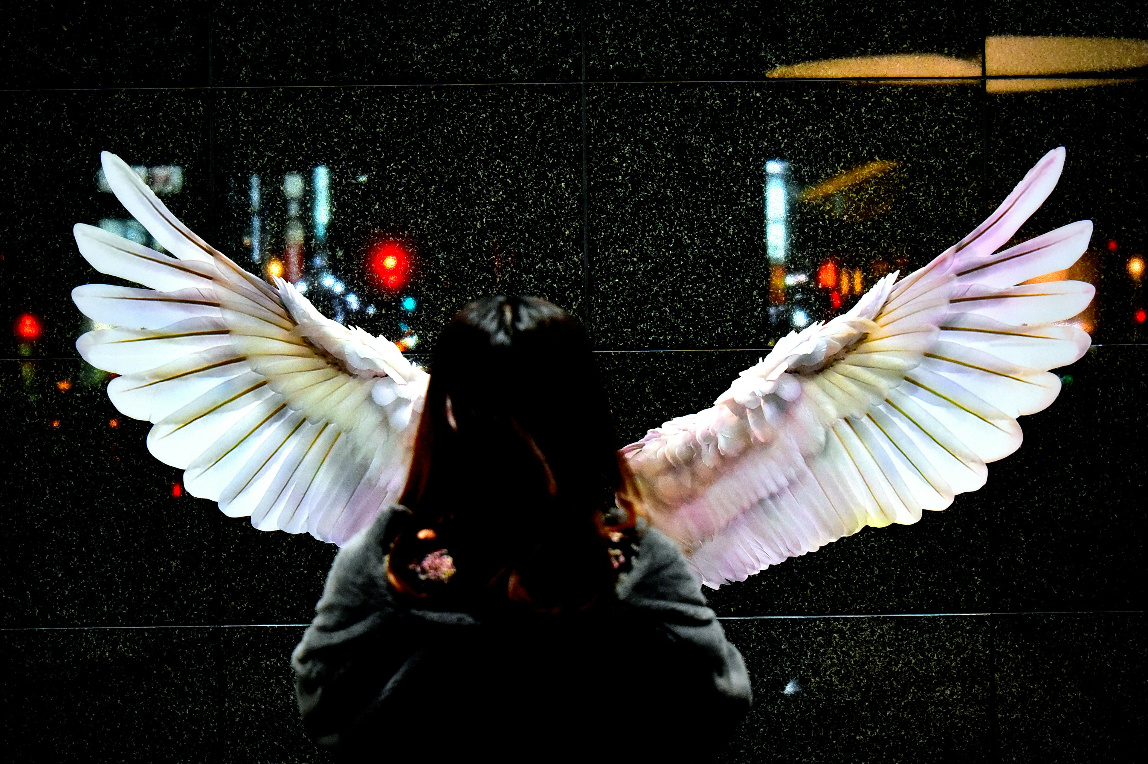 A woman standing with large white angel wings art in the background