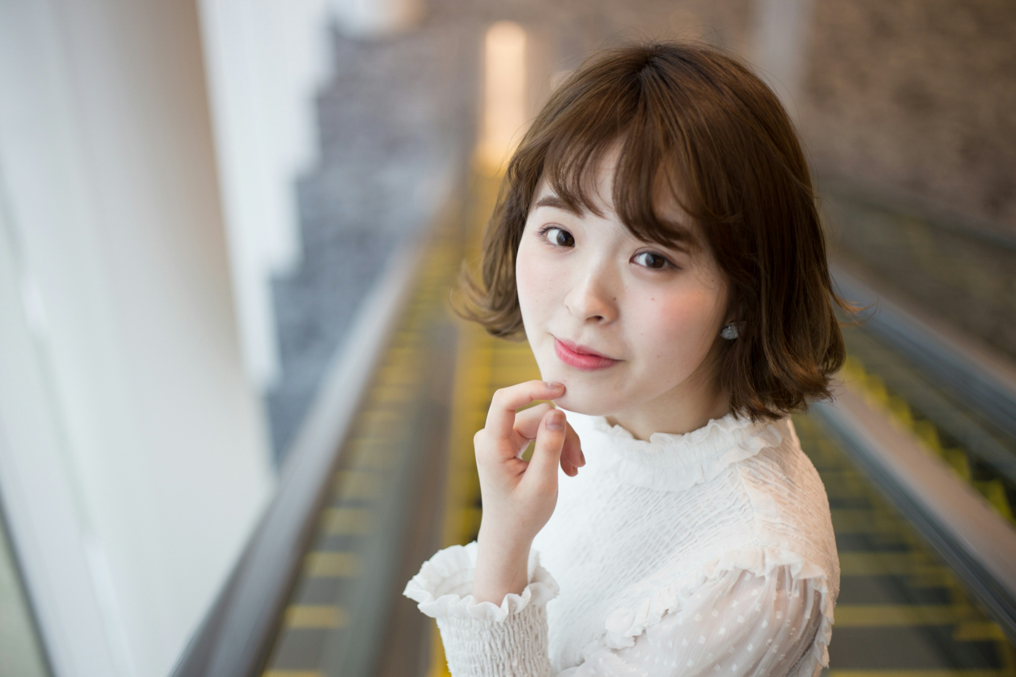 Portrait of a woman near an escalator wearing a white blouse and smiling