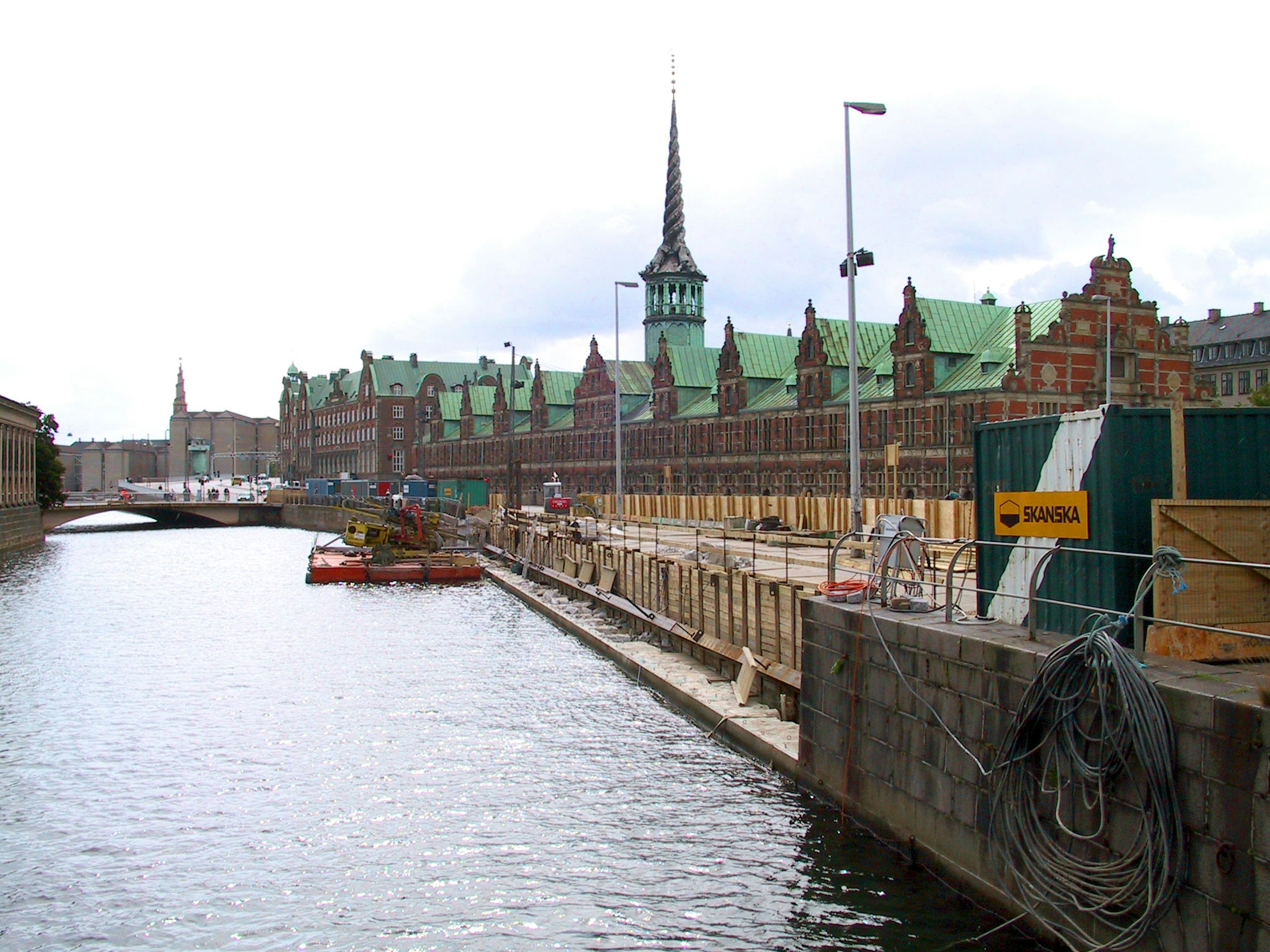 Edificios históricos a lo largo del canal con techos verdes y una alta aguja