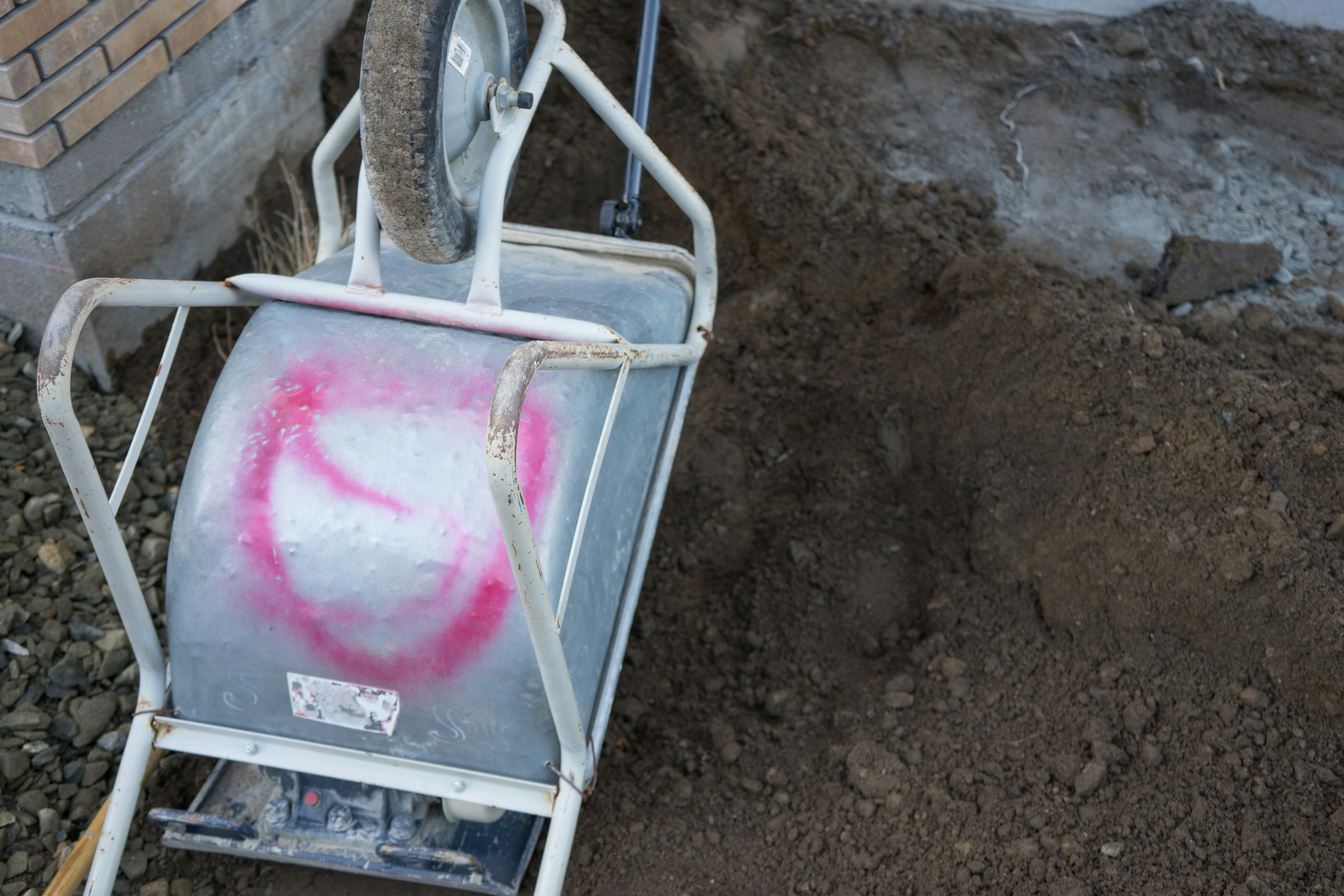 Carrello a mano con segni rosa accanto a terreno appena scavato