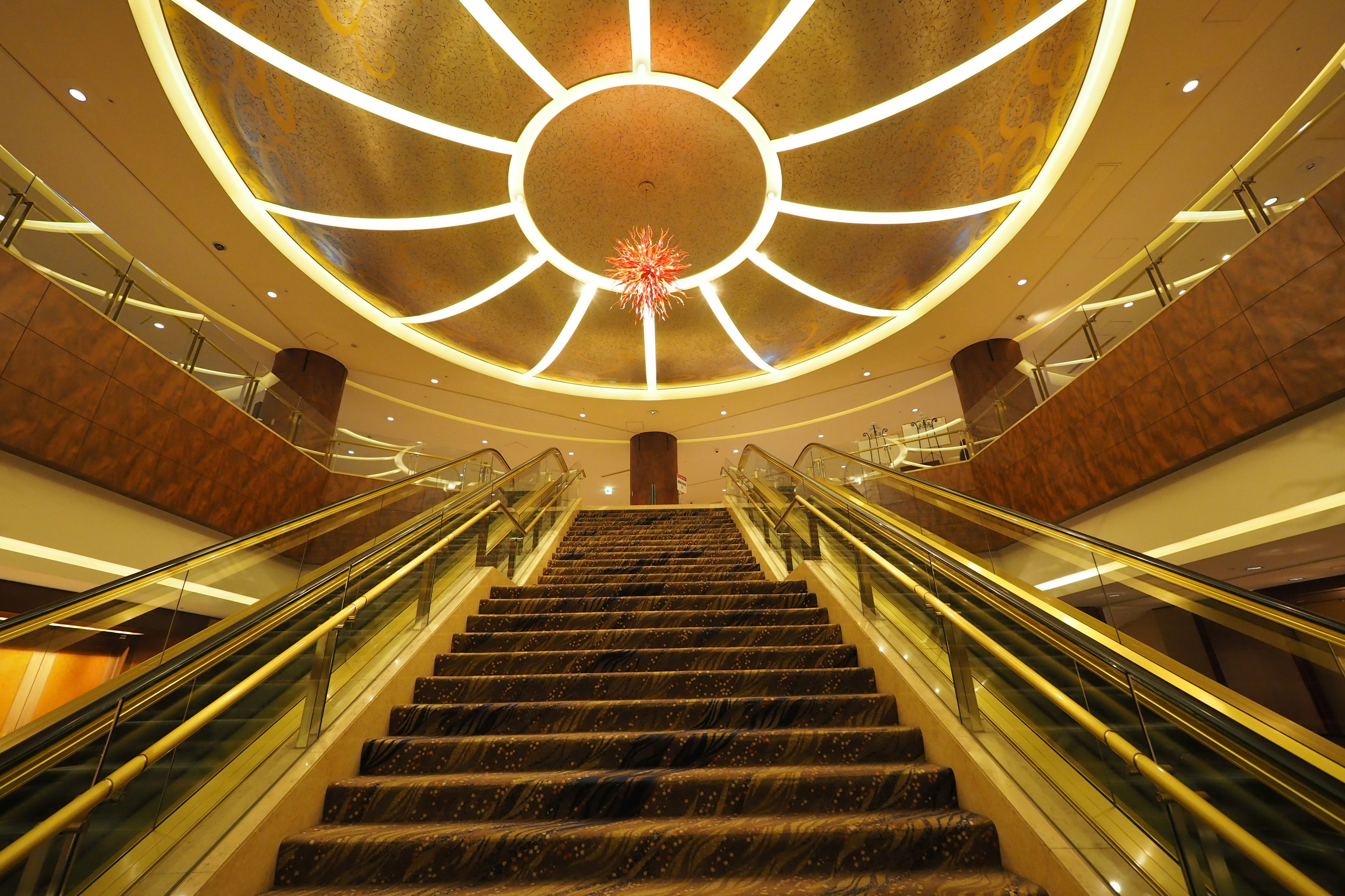 Luxurious escalator leading to a beautifully designed ceiling with warm lighting