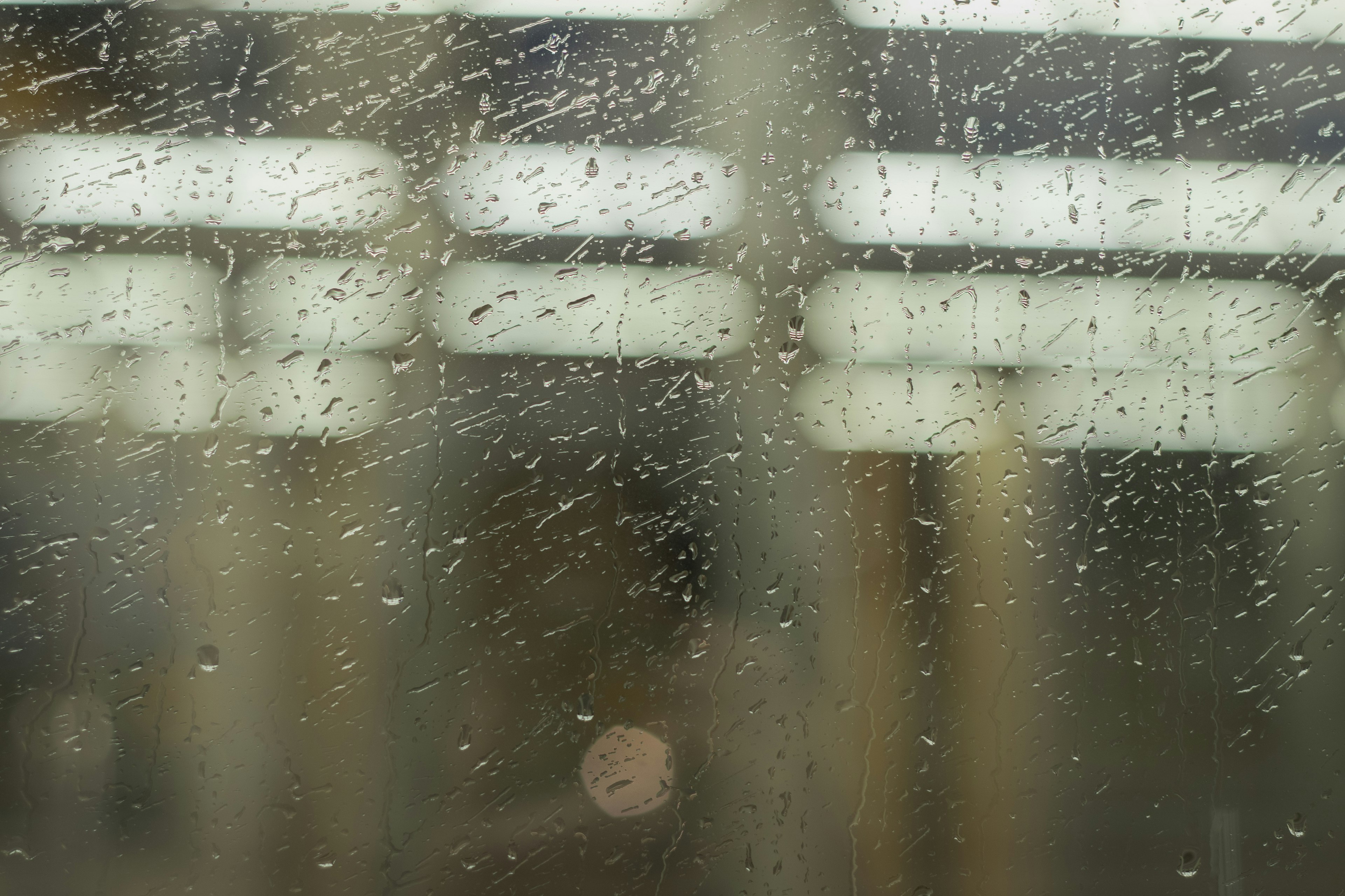 雨に濡れた窓の近くからの視界で、ぼんやりとした明るい光が見える