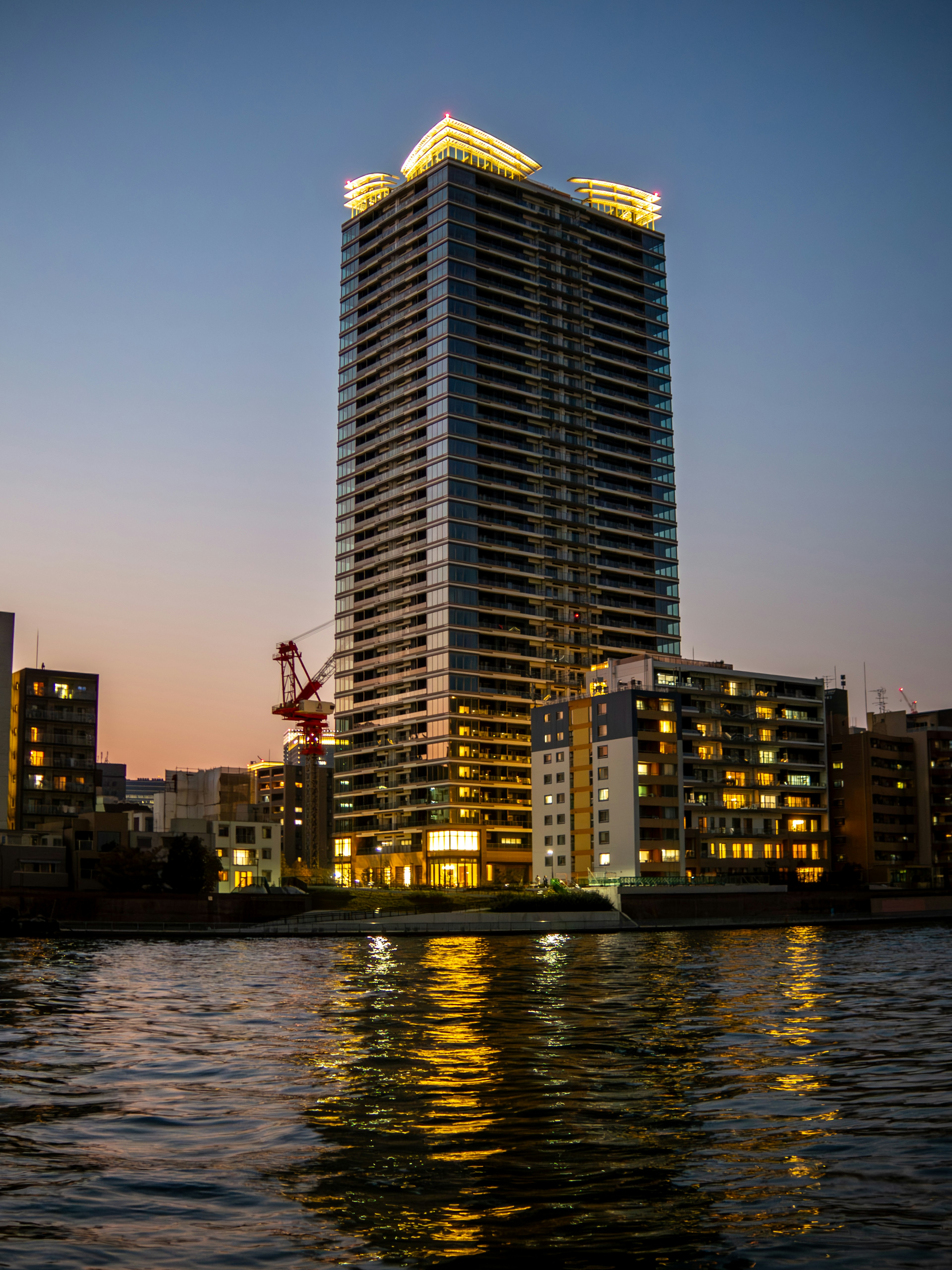 A stunning view of a skyscraper along the river at twilight