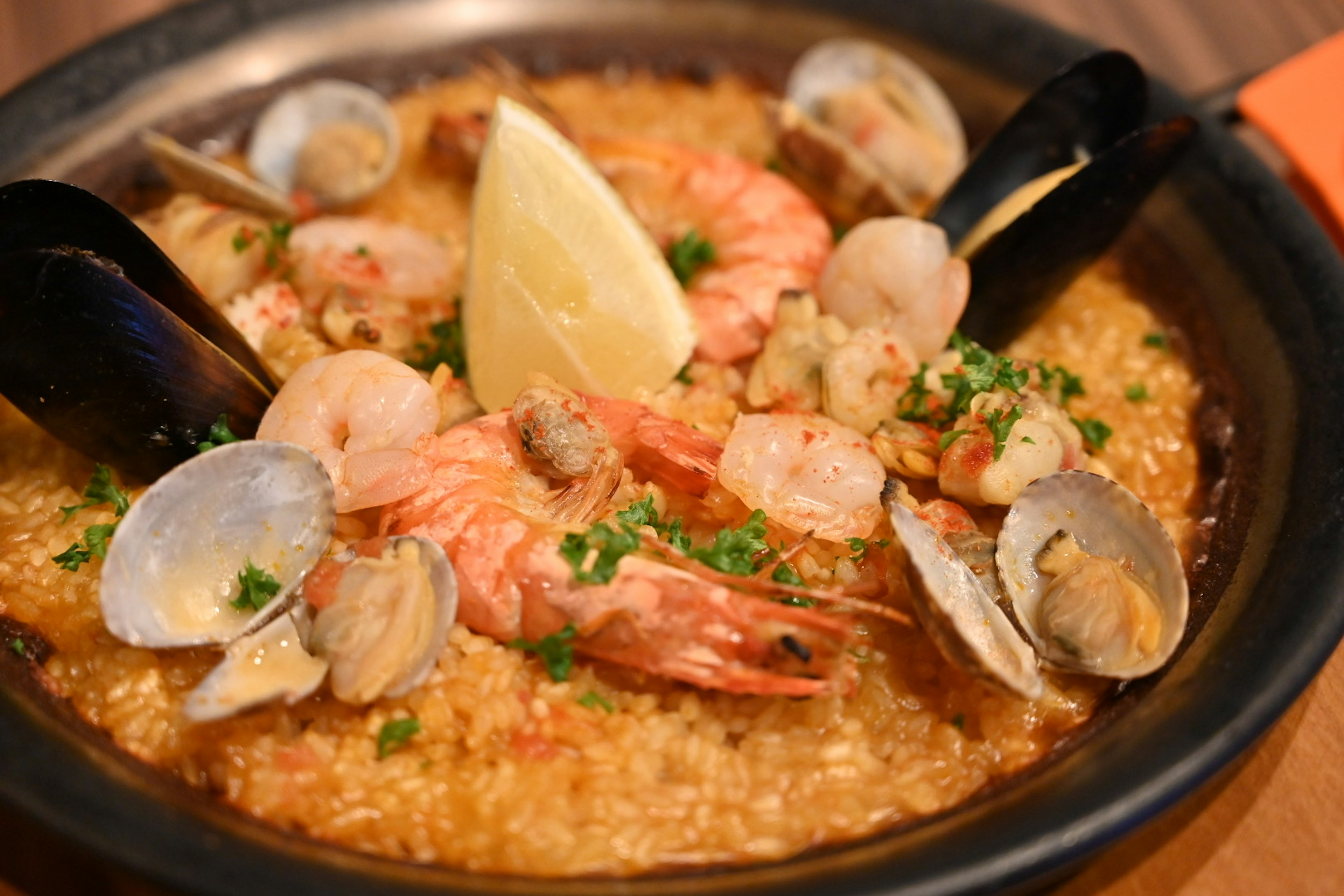 Meeresfrüchte-Paella mit Garnelen und Muscheln garniert mit Zitronenscheiben