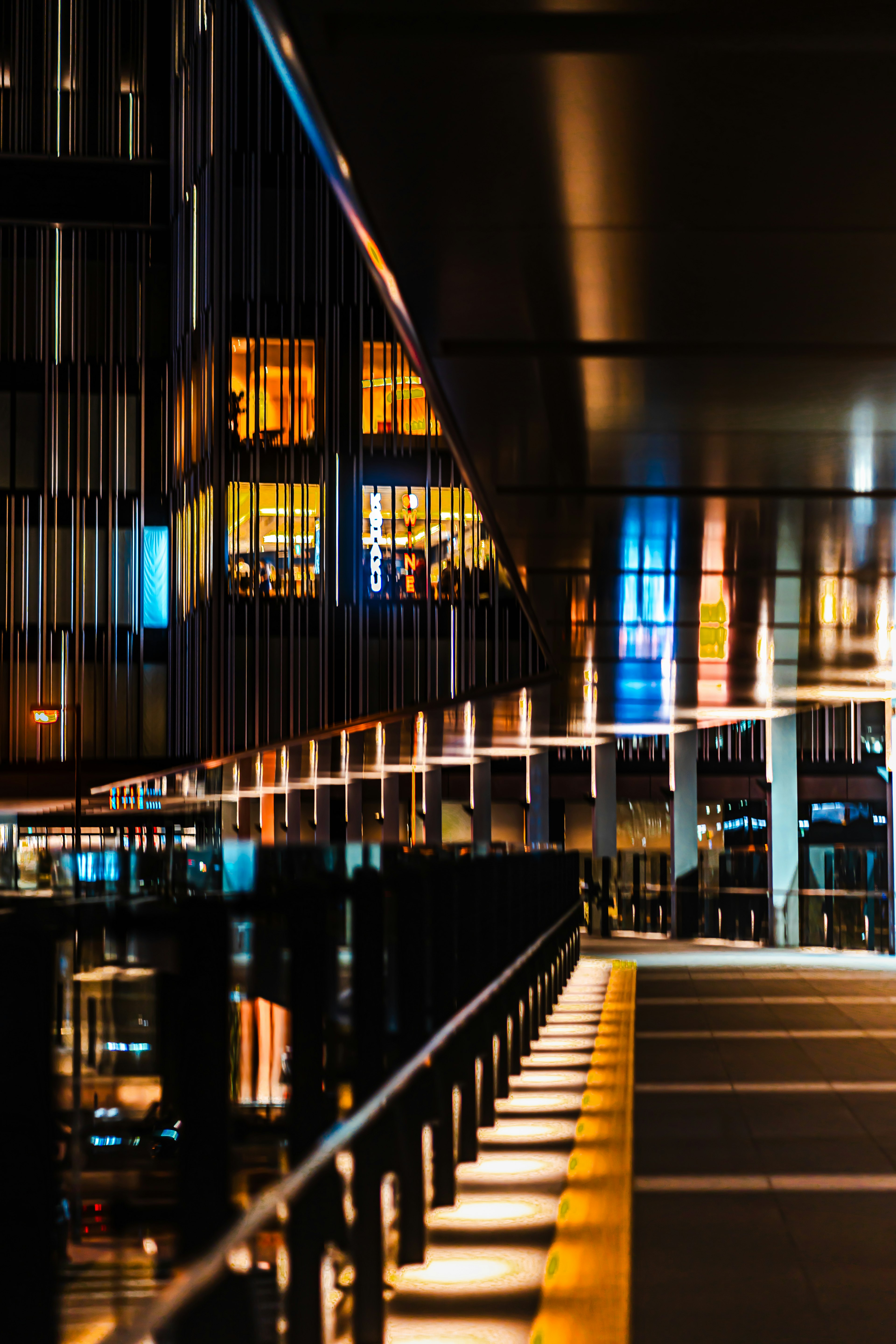 Scène nocturne d'un bâtiment moderne avec des reflets lumineux et un contraste de couleurs